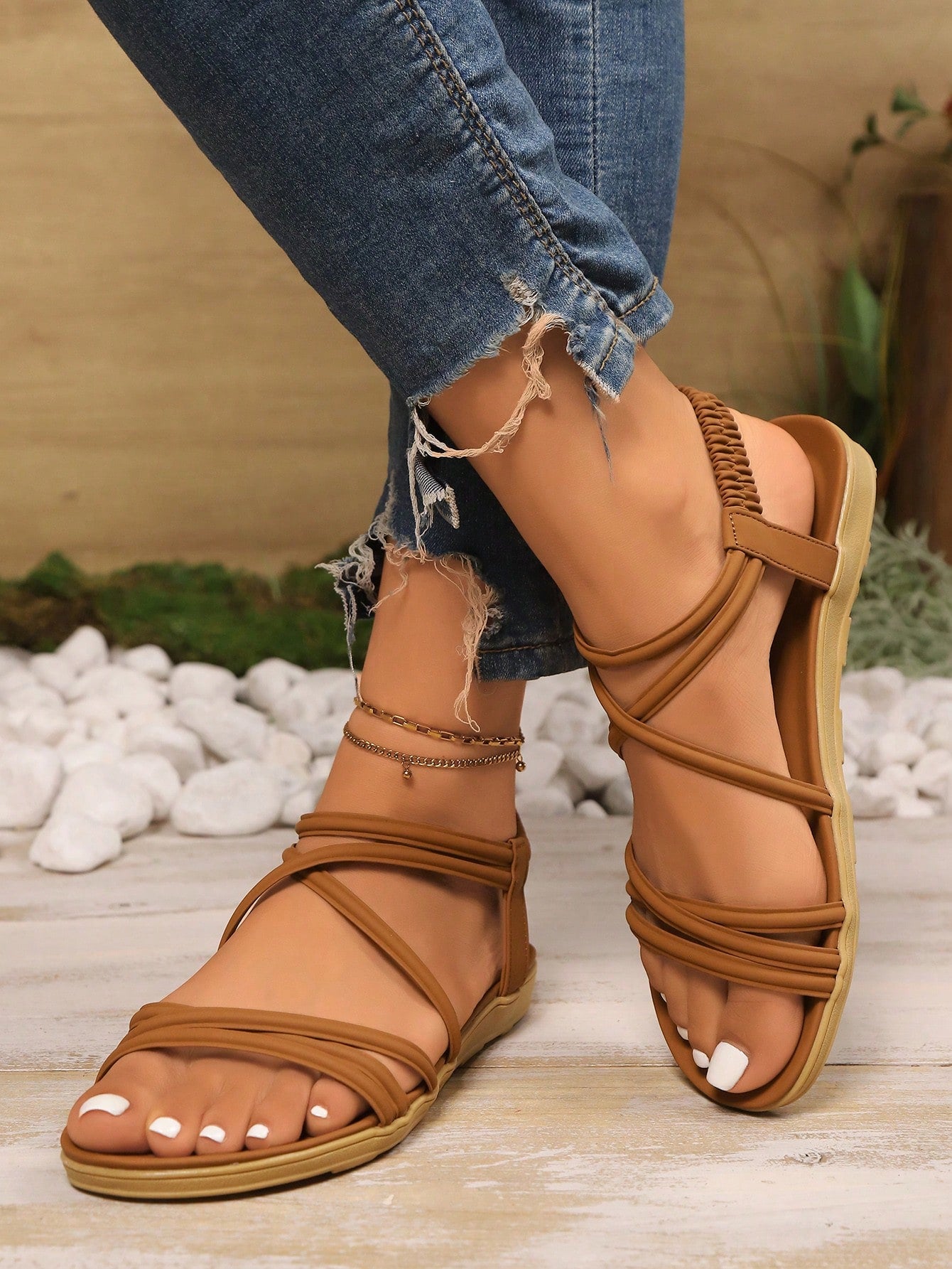 Women's beige flat sandals with criss cross straps, ankle strap, and open toe.