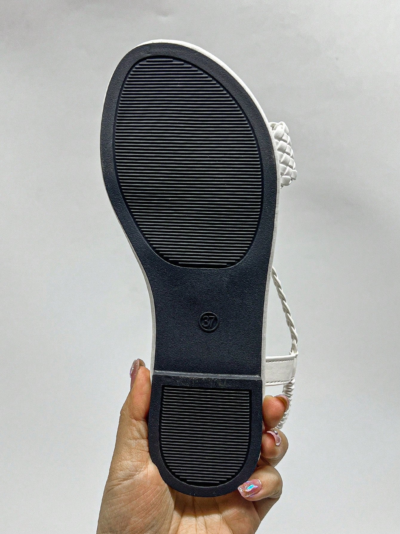 White women’s Roman-style flat gladiator sandals with braided woven straps and open toe, casual beach and summer footwear.
