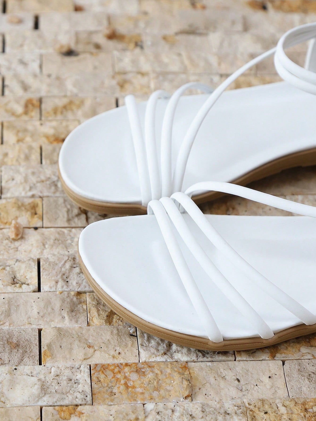 Pair of women's elegant criss cross flat sandals with open toe design, ankle strap, and buckle detail in PU leather.