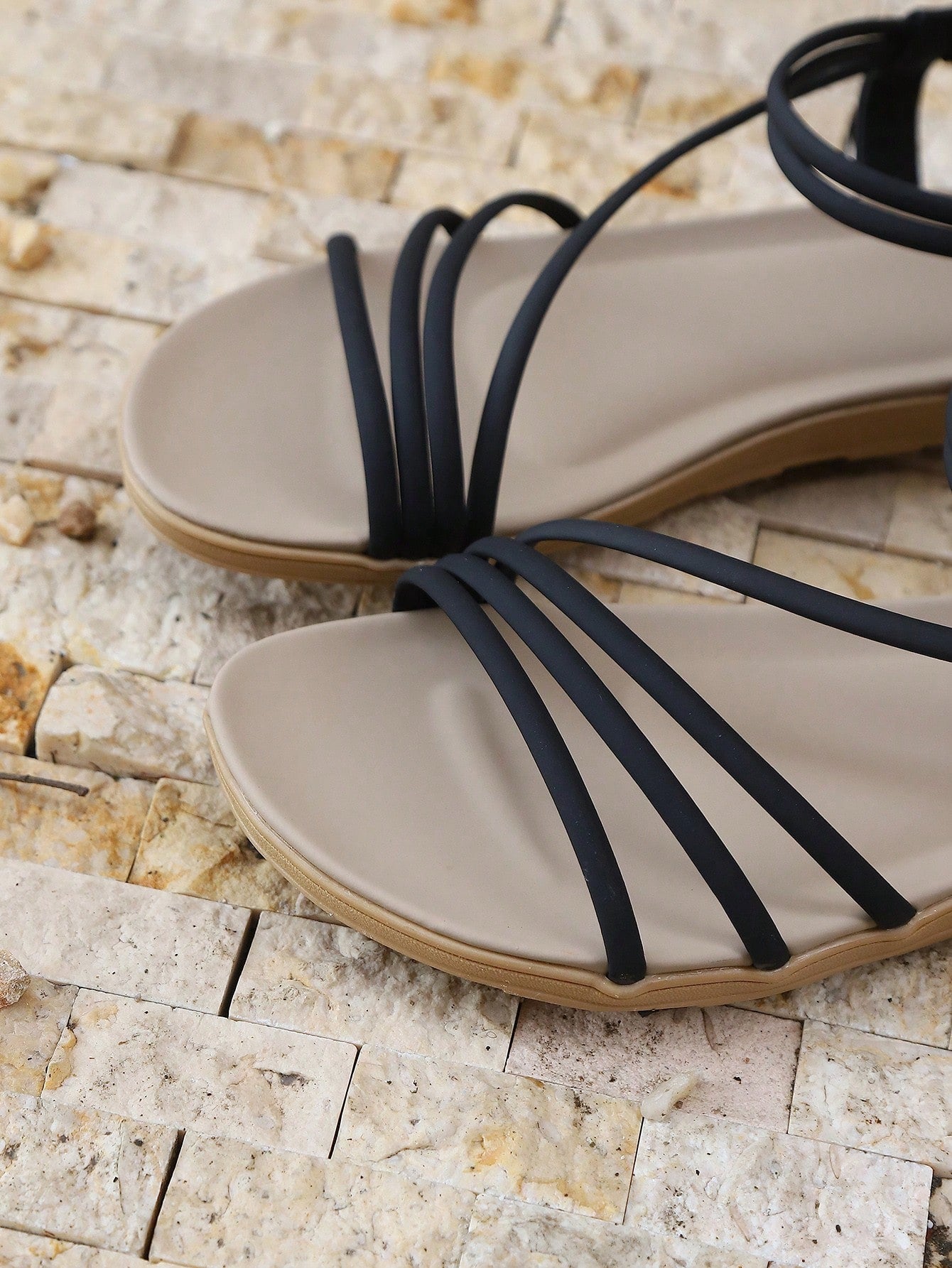 Pair of women's elegant criss cross flat sandals with open toe design, ankle strap, and buckle detail in PU leather.