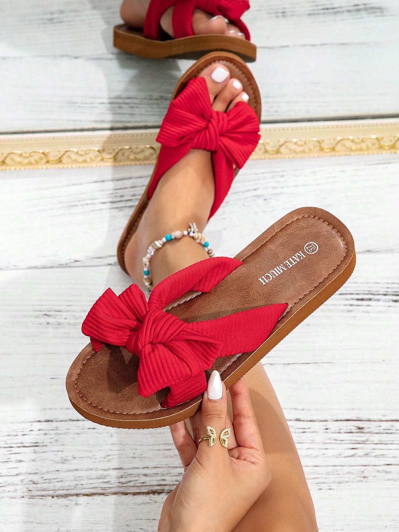 Women's flat slide sandals with ruched fabric, bow accent, and fringe detail, suitable for outdoor vacation wear.