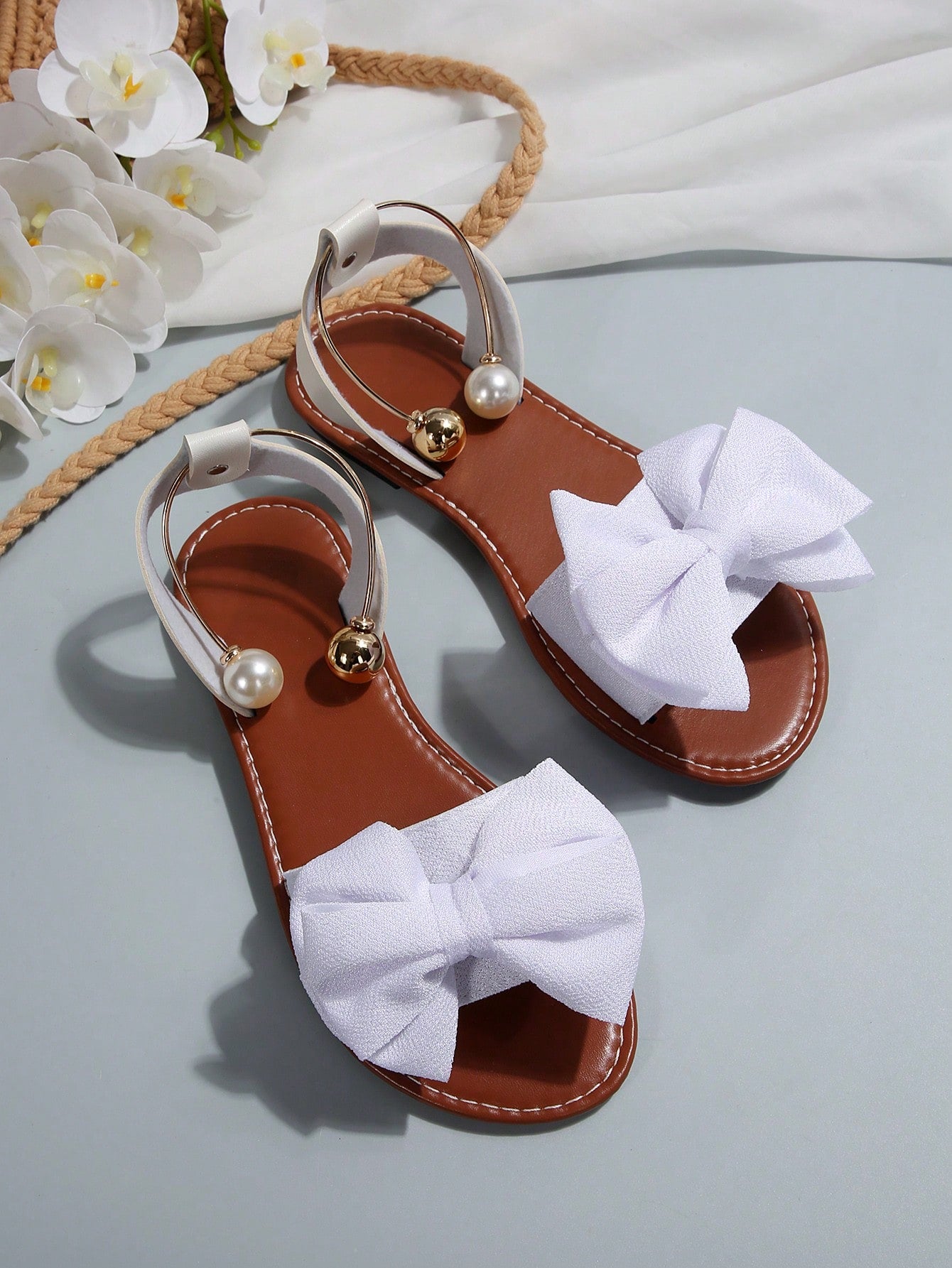 Women’s flat open-toe sandals with faux pearl decor and ankle strap design, featuring a microfiber leather upper and beach-ready fashion style.