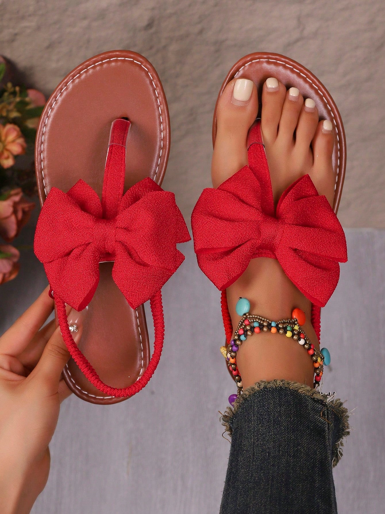 Pair of women’s solid color bohemian flat sandals with fabric bow detail, toe post thong design, and slide-on style for casual beach, outdoor, vacation, and home wear.