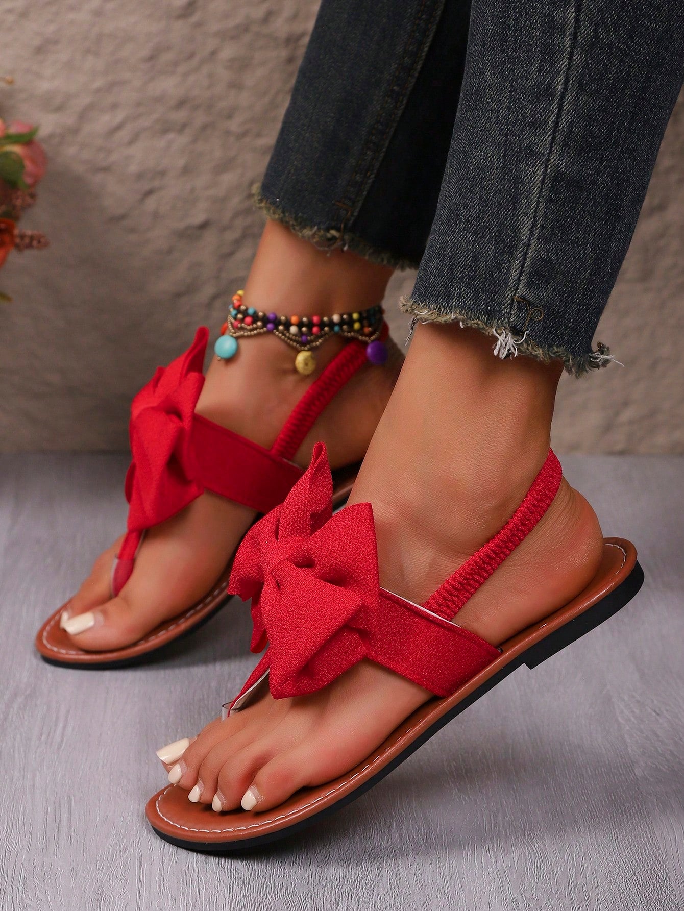 Pair of women’s solid color bohemian flat sandals with fabric bow detail, toe post thong design, and slide-on style for casual beach, outdoor, vacation, and home wear.