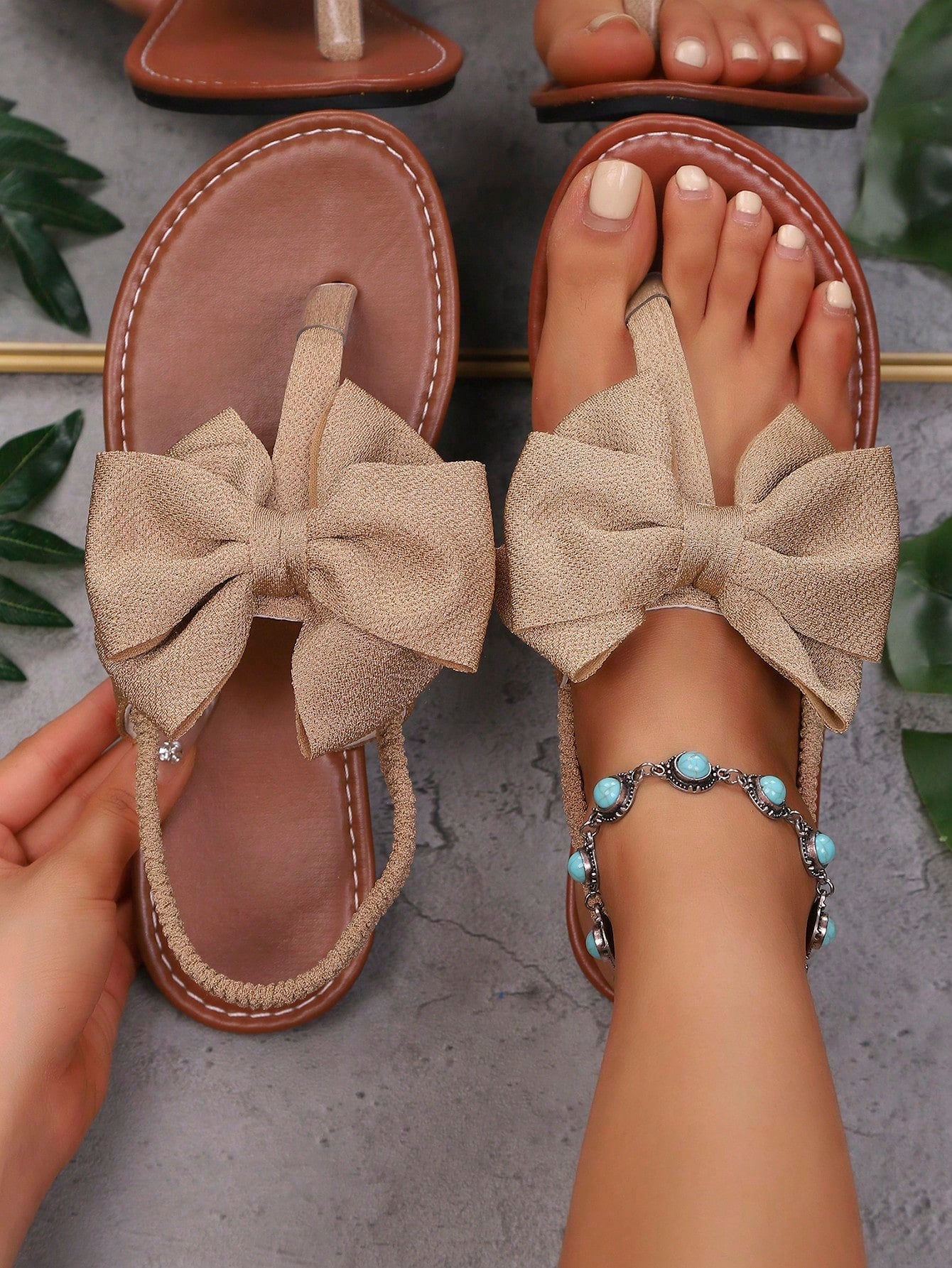 Pair of women’s solid color bohemian flat sandals with fabric bow detail, toe post thong design, and slide-on style for casual beach, outdoor, vacation, and home wear.