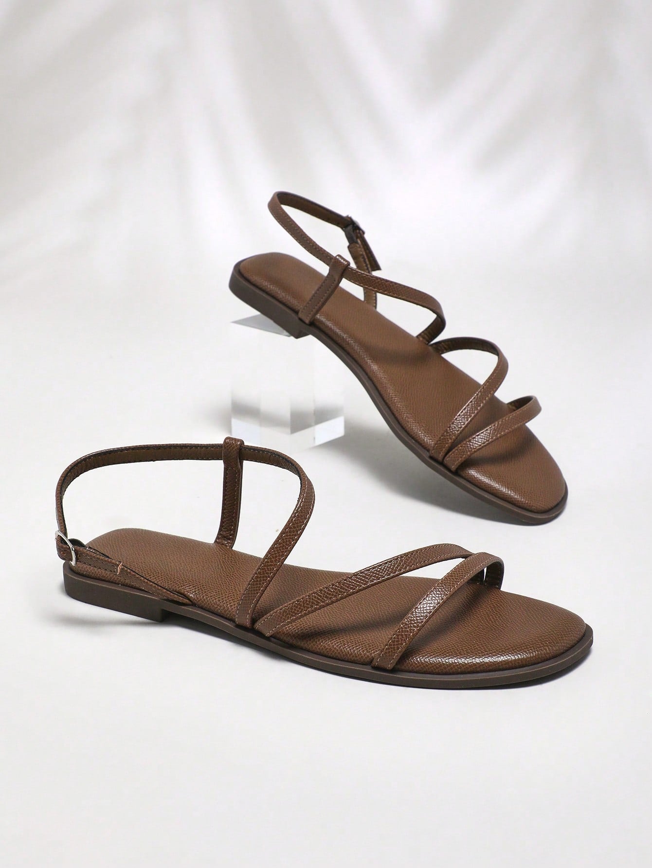 Women's flat open-toe sandals featuring a buckle detail and PU leather construction with a flat sole.