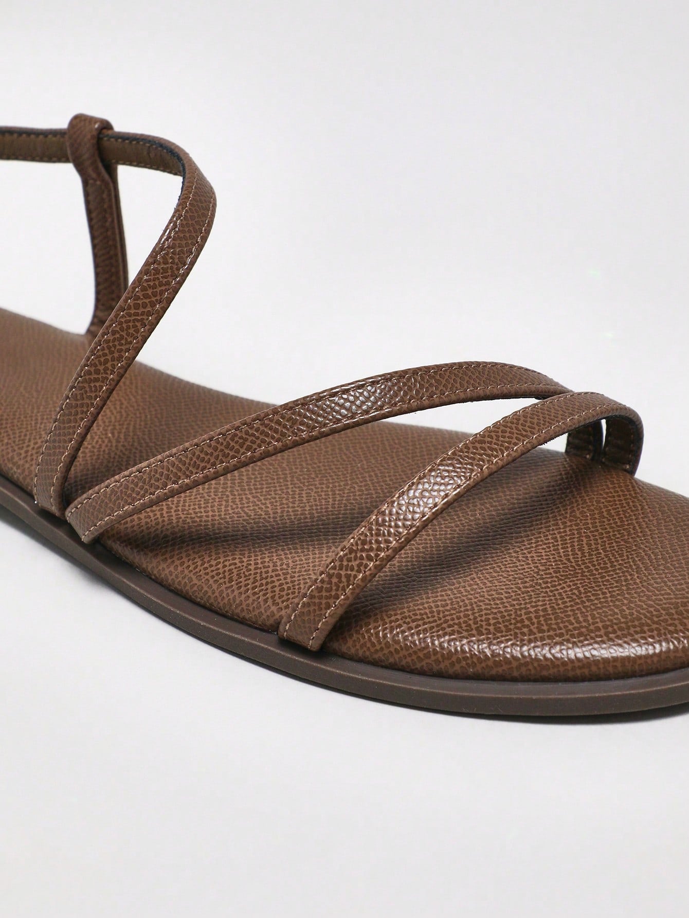 Women's flat open-toe sandals featuring a buckle detail and PU leather construction with a flat sole.