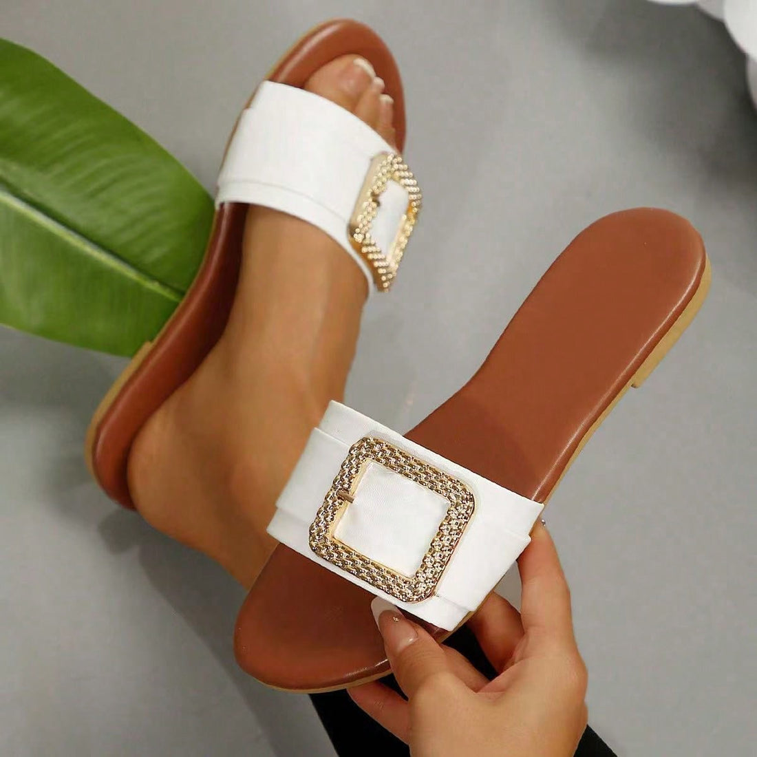 Women’s wide fit white flat slide mules with draped strap detail, square buckle accent, and open toe design, suitable for summer daily wear, vacation, and outdoor activities.