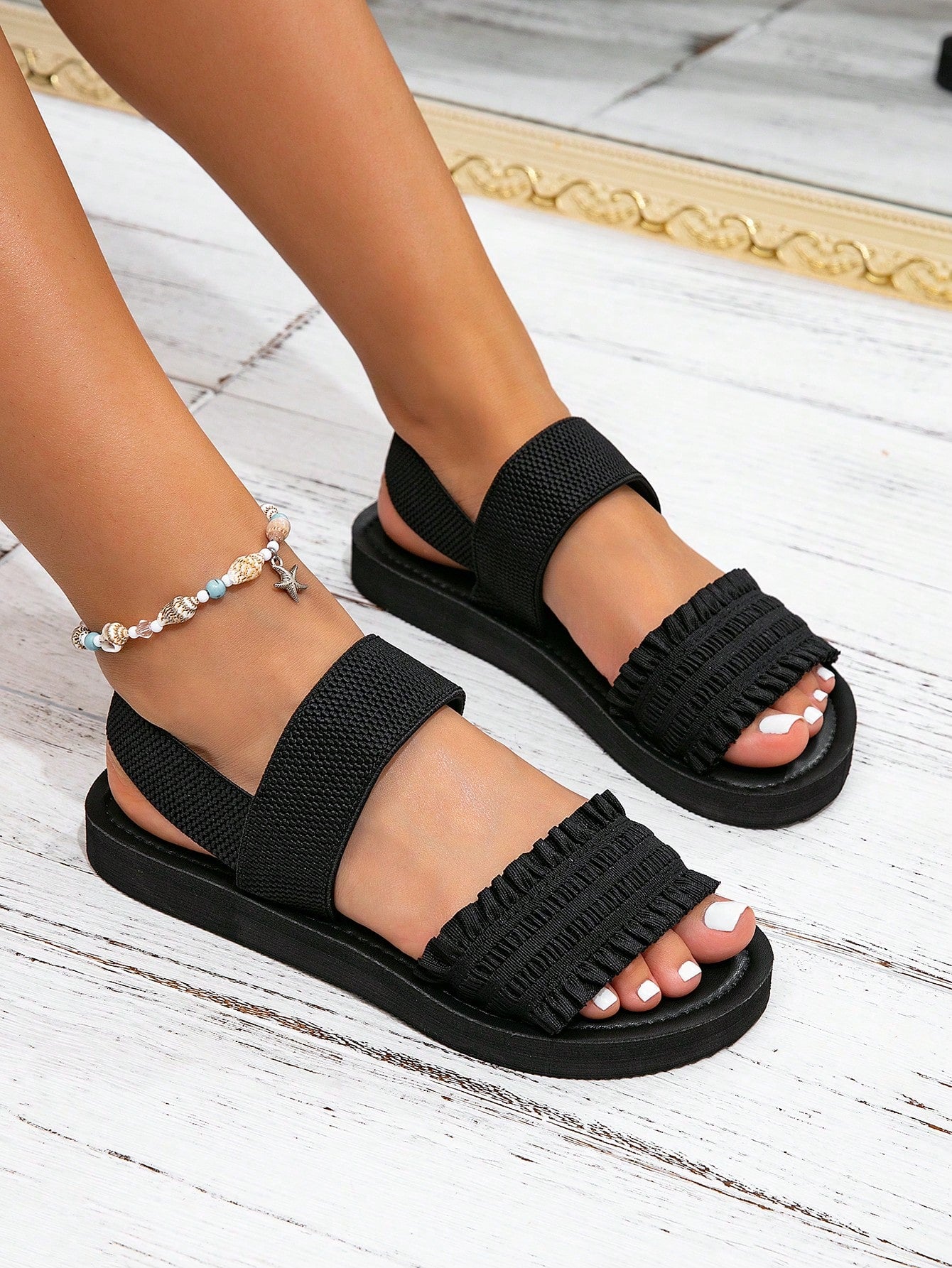 Women's flat slide sandals with ruched fabric, bow accent, and fringe detail, suitable for outdoor vacation wear.