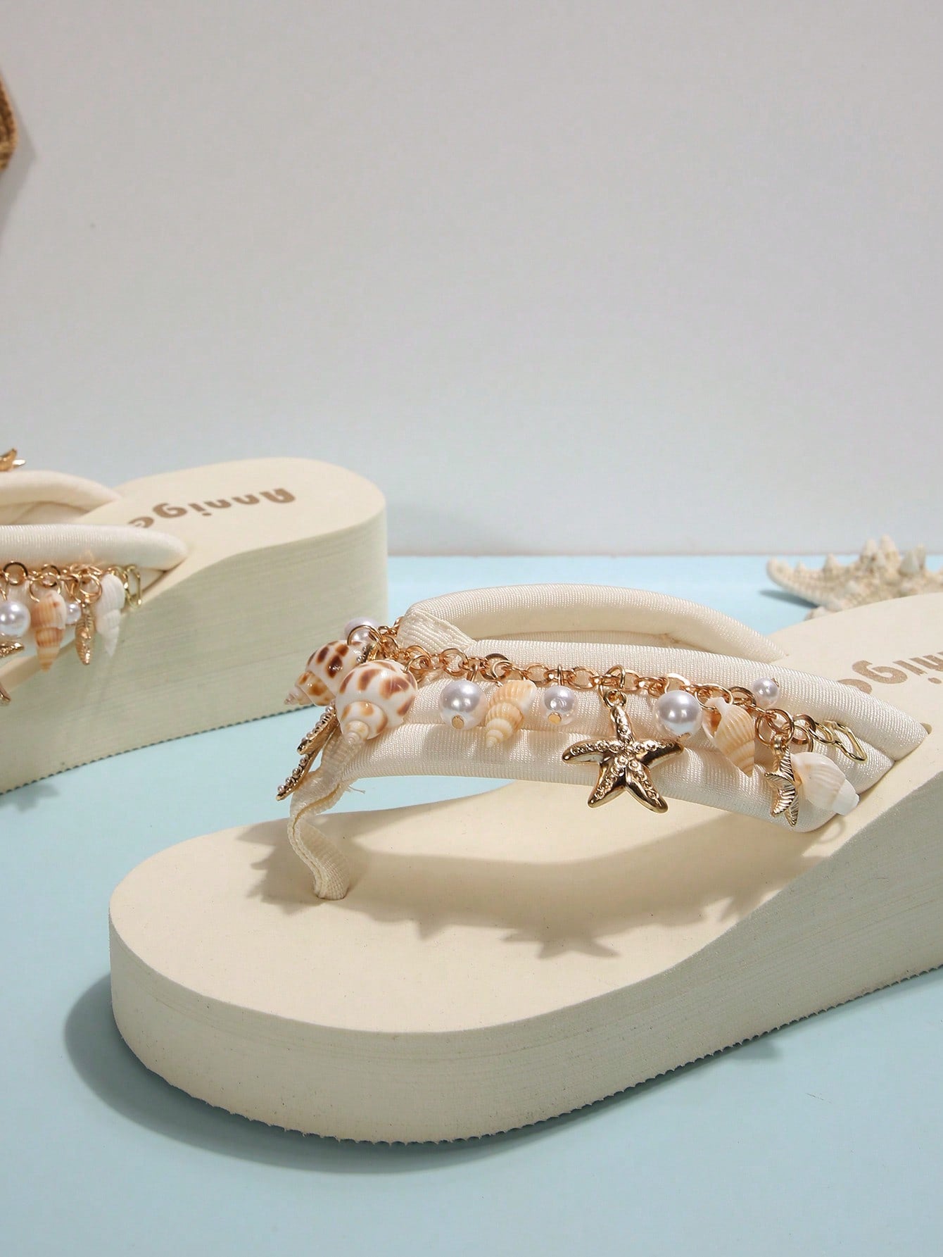 Beige women’s platform wedge slip-on sandals with toe post, shell chain decor, and flower rhinestone details, designed in a beach holiday flip-flop style.