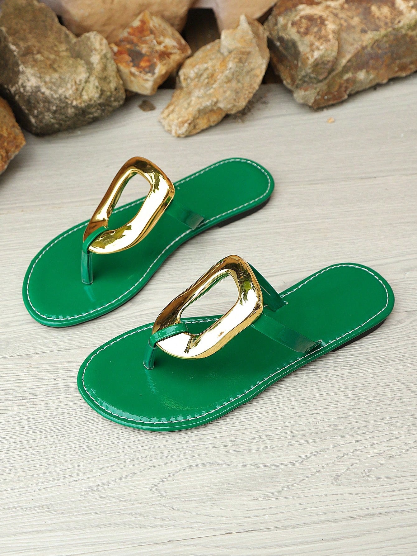 Women’s gold flat slide sandals with open toe post design and metal buckle detail, shown as fashionable outdoor summer footwear.
