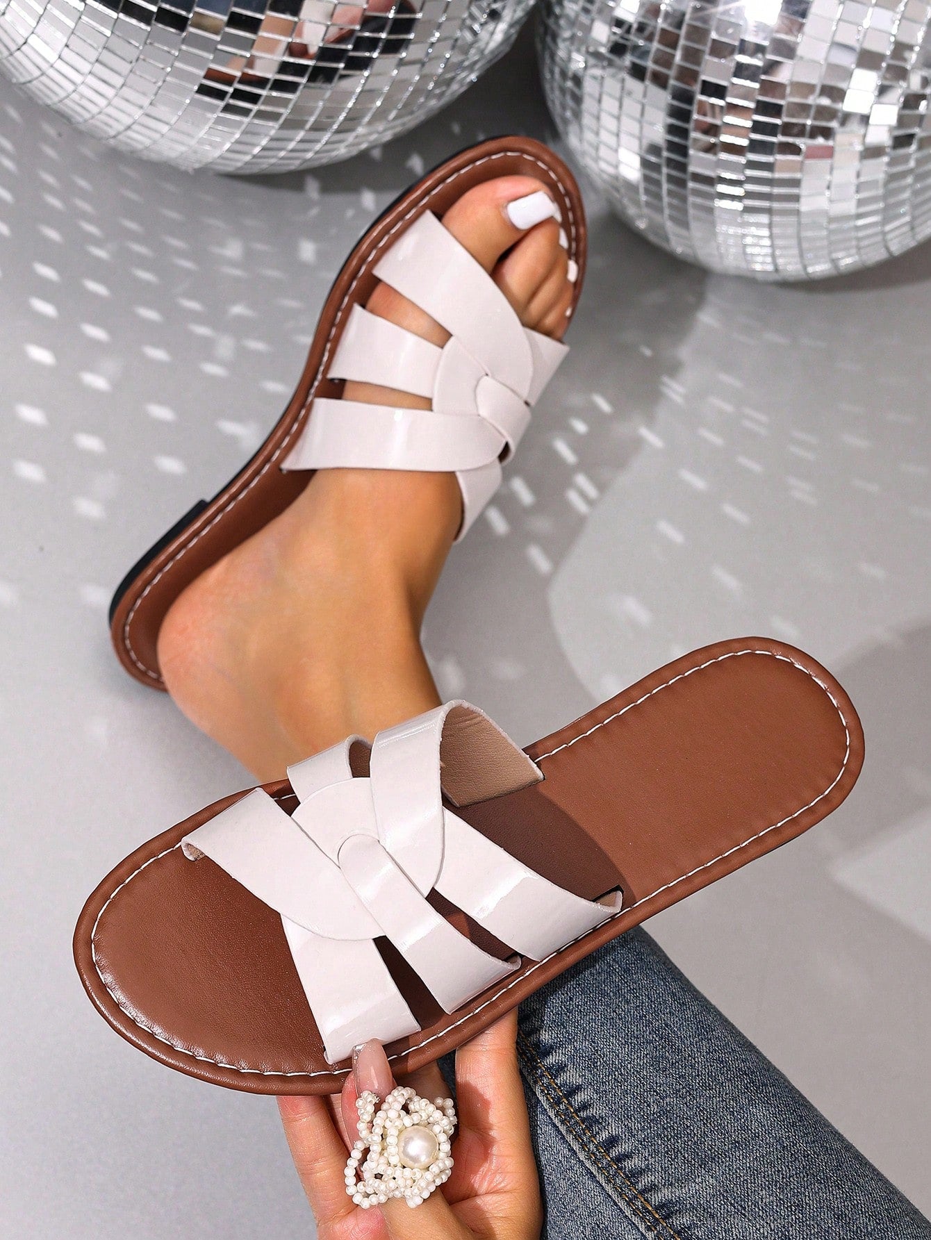Pair of women’s open-toe flat slide sandals with an H-shaped strap, braided and embossed details, and a minimalist slip-on design suitable for casual outdoor wear.