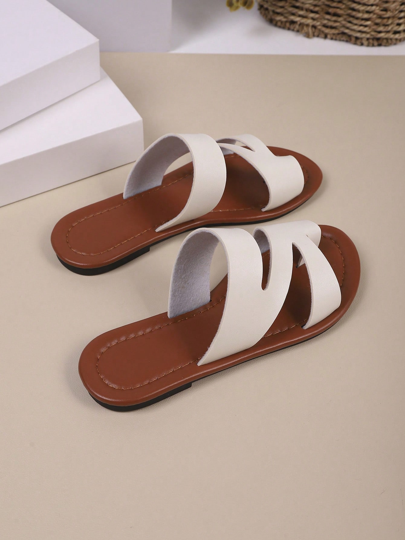 Women’s minimalist flat flip flop sandals with toe post and cut-out detail, lightweight design for beach and vacation wear, in white and brown tones.