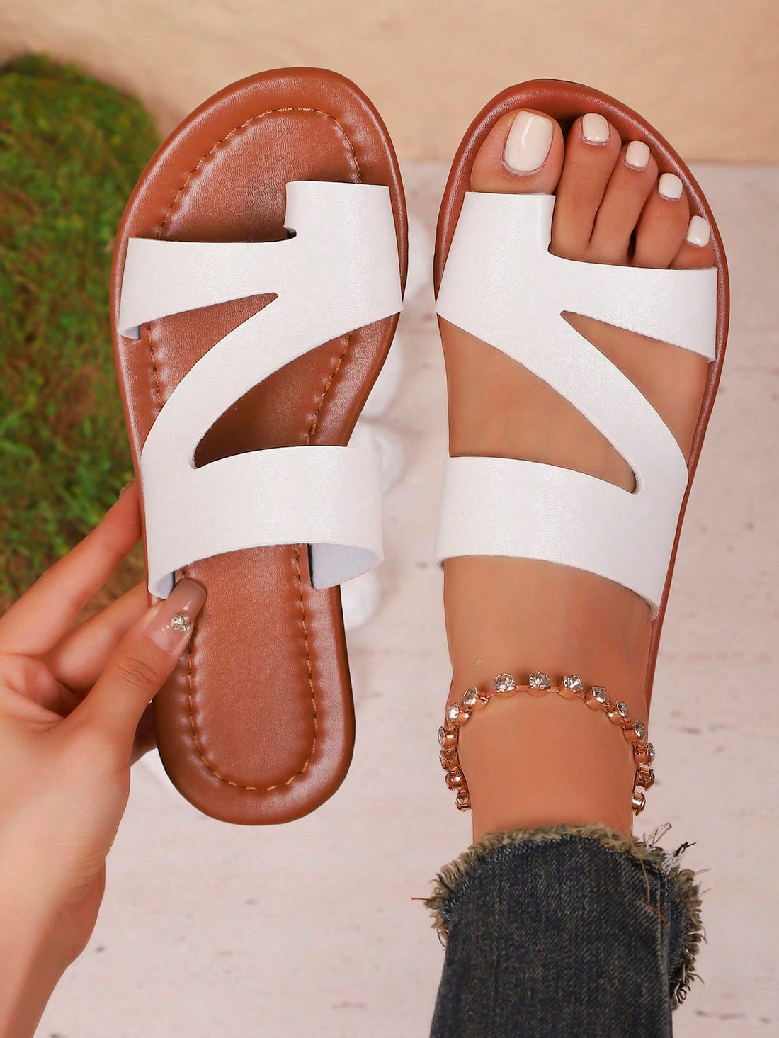 Women’s minimalist flat flip flop sandals with toe post and cut-out detail, lightweight design for beach and vacation wear, in white and brown tones.