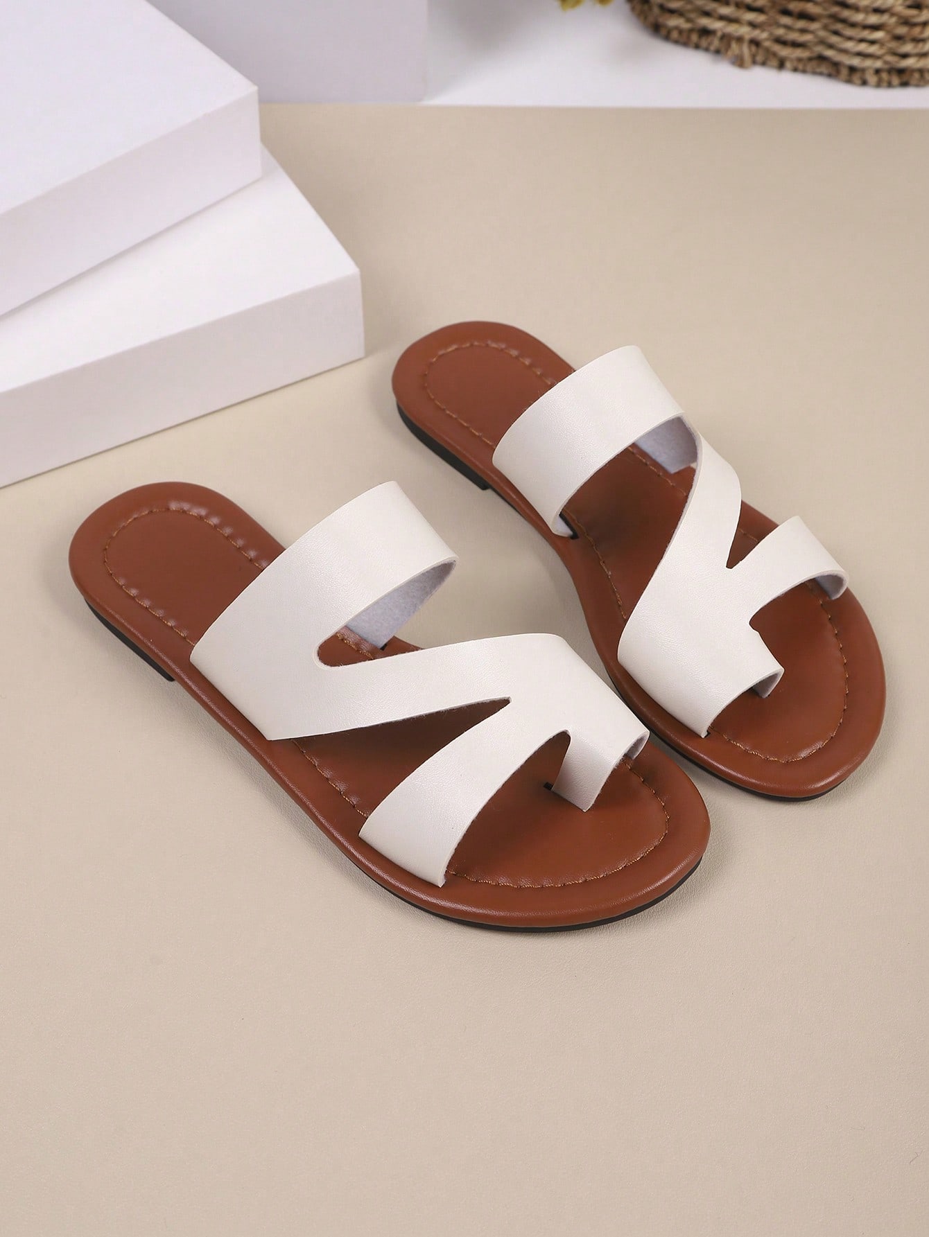Women’s minimalist flat flip flop sandals with toe post and cut-out detail, lightweight design for beach and vacation wear, in white and brown tones.
