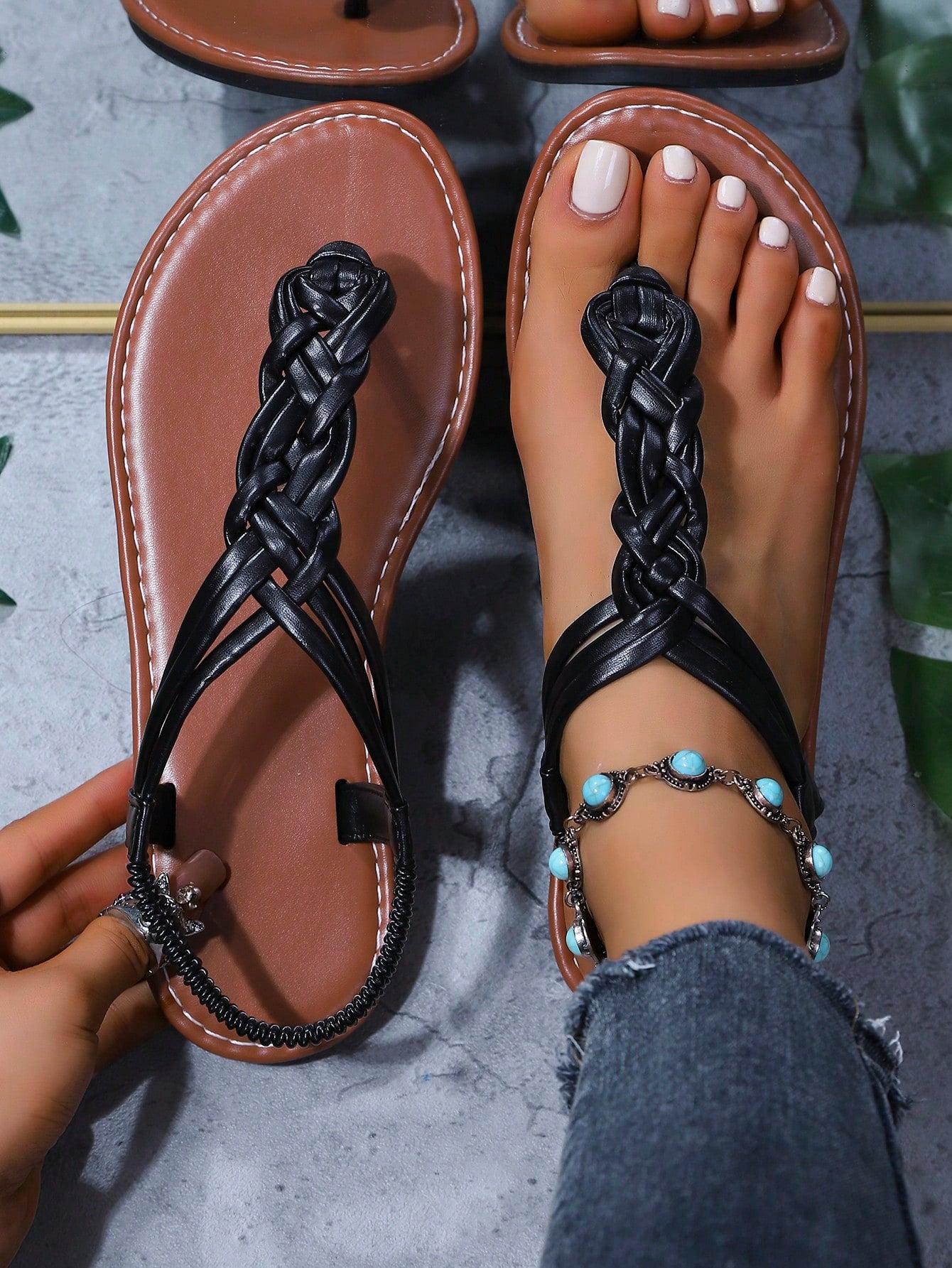 Women's black handmade woven flat thong gladiator sandals with braided criss-cross straps, toe post design, and flat rubber sole.