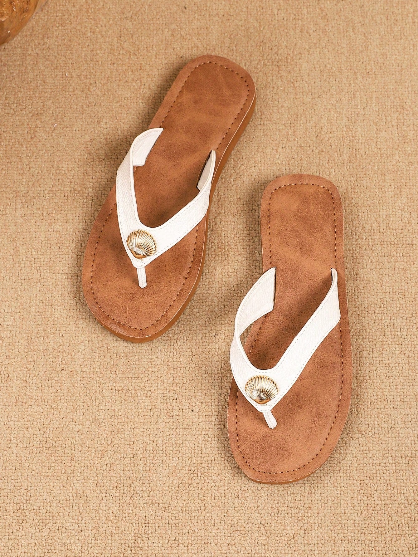 Brown vintage chic flip flops with metal shell decor, toe-post slide design, criss cross straps, and wedge sole for casual beach and outdoor wear.