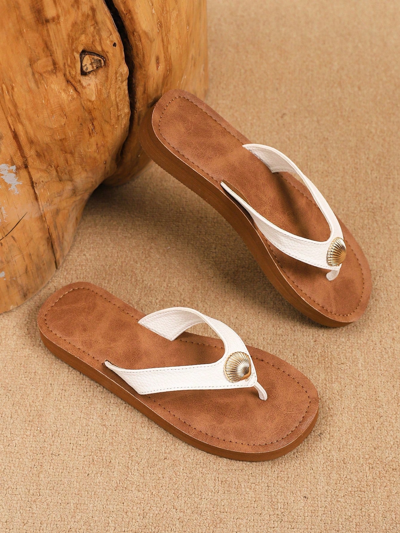 Brown vintage chic flip flops with metal shell decor, toe-post slide design, criss cross straps, and wedge sole for casual beach and outdoor wear.