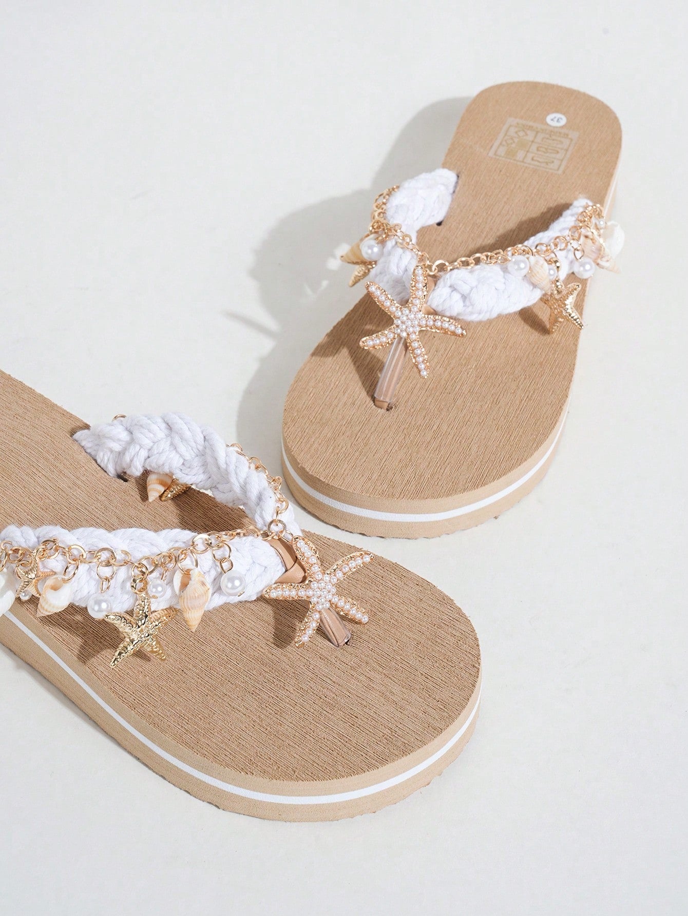 Handmade women’s beach flip flop sandals with shell and starfish rhinestone decorated woven straps, flat thong style, and lightweight non-slip sole.