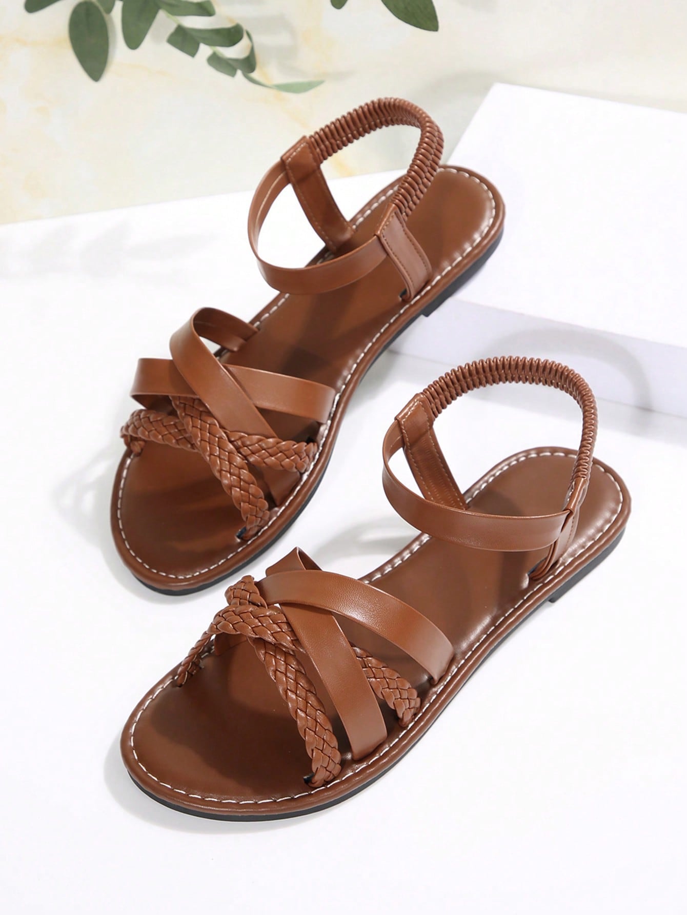Women’s flat slide sandals with criss-cross straps, open toe, and braid detail, designed for lightweight casual and beach wear.
