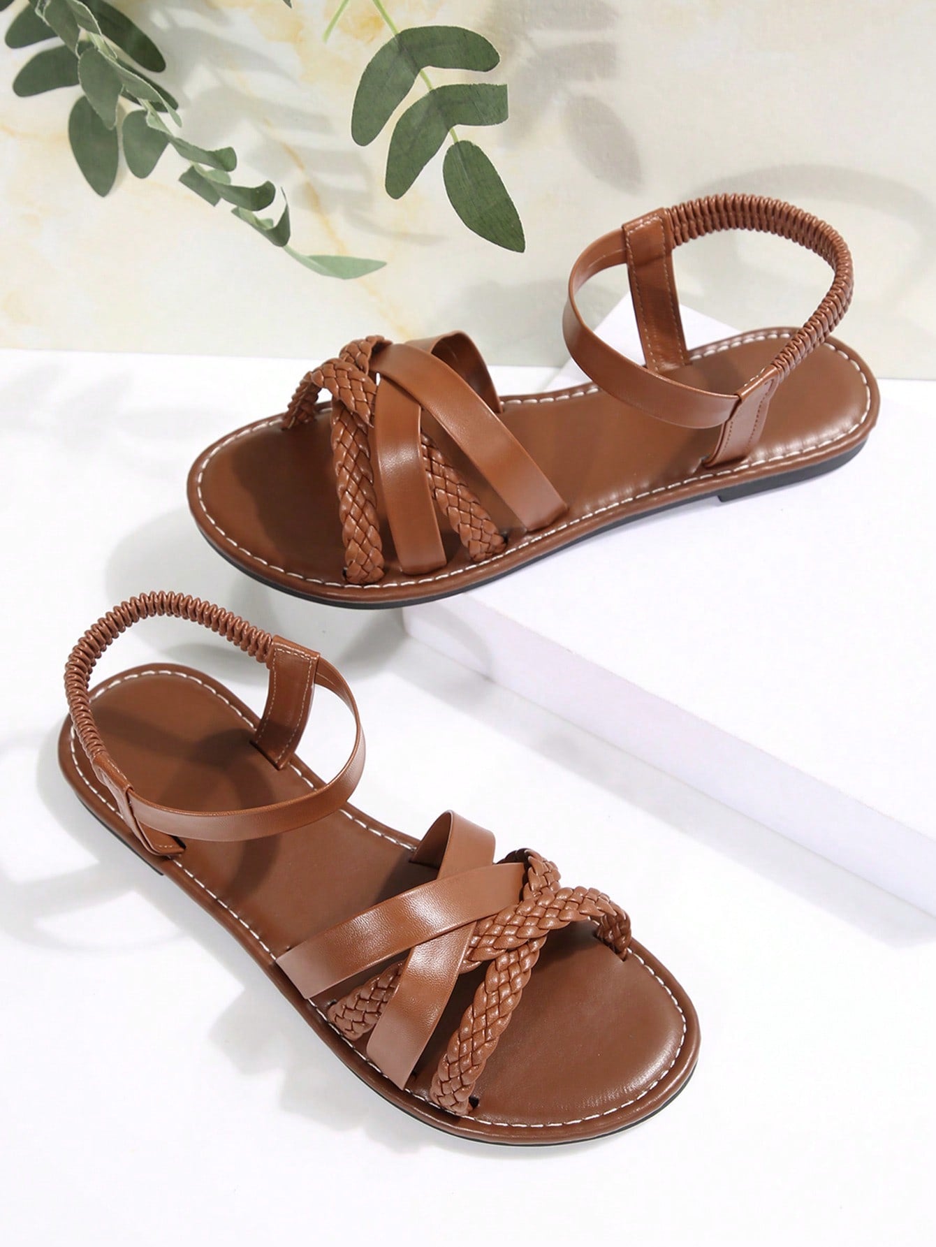 Women’s flat slide sandals with criss-cross straps, open toe, and braid detail, designed for lightweight casual and beach wear.