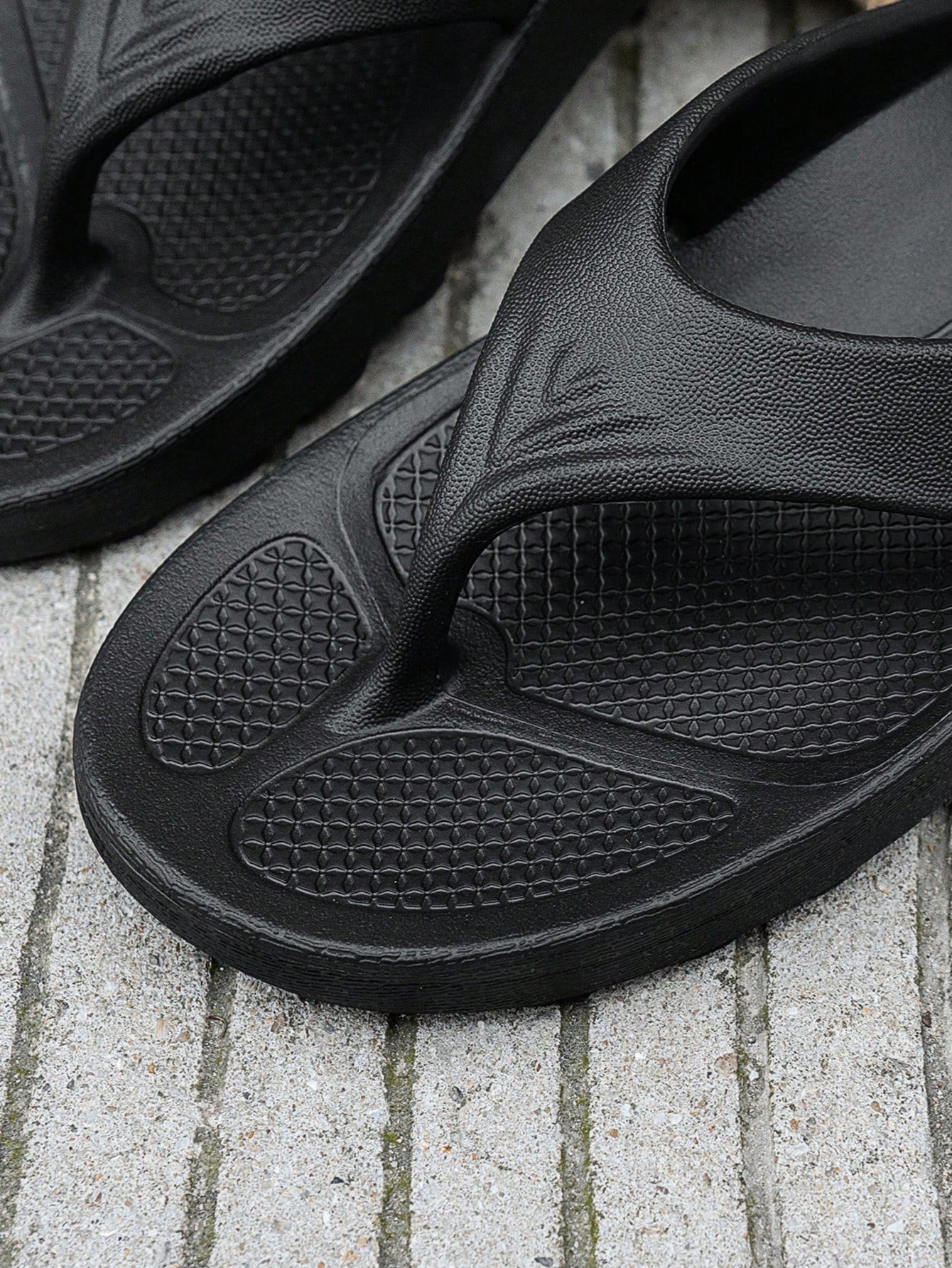 Women's solid color flip flops with open-toe design, flat sole, and cut-out details, suitable for casual indoor or outdoor wear at the beach or pool.
