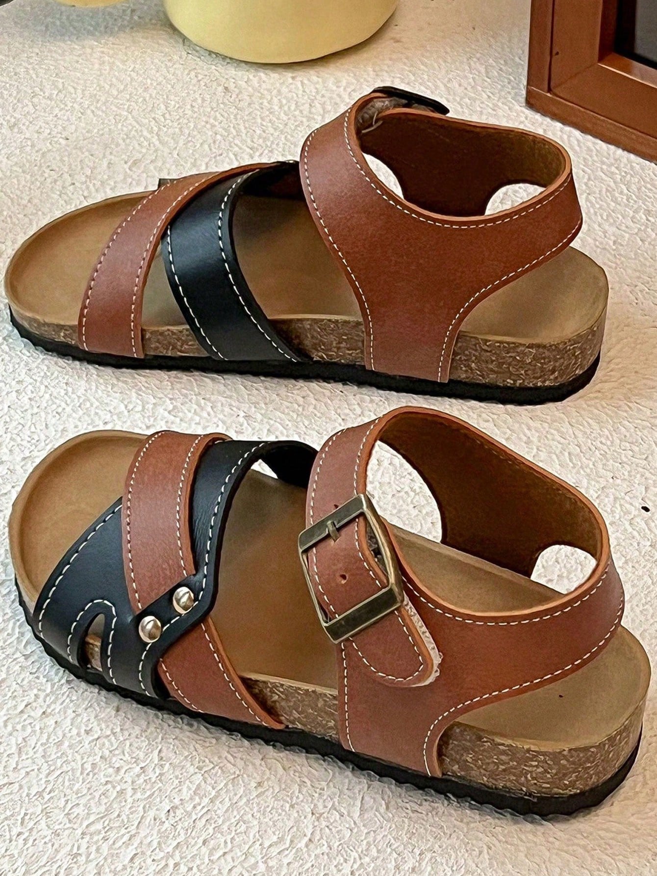 Pair of girls' pink open-toe flat sandals with ankle straps, buckle details, and a non-slip black rubber outsole.