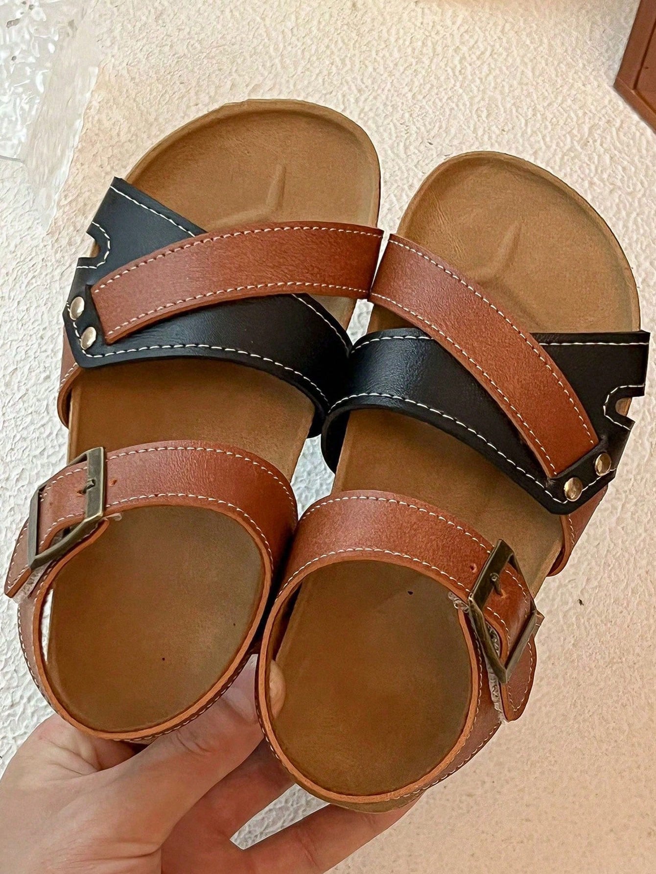 Pair of girls' pink open-toe flat sandals with ankle straps, buckle details, and a non-slip black rubber outsole.