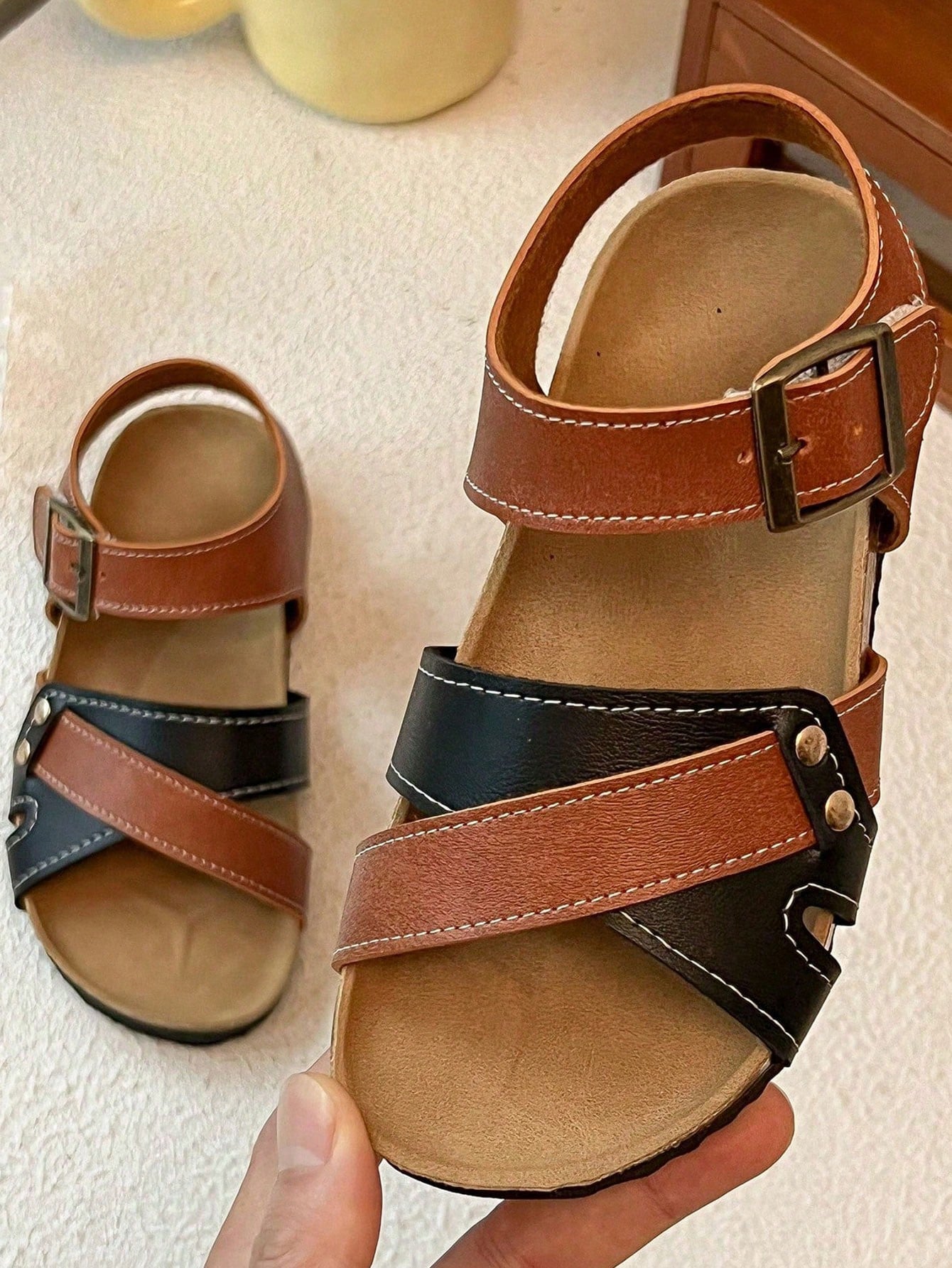 Pair of girls' pink open-toe flat sandals with ankle straps, buckle details, and a non-slip black rubber outsole.