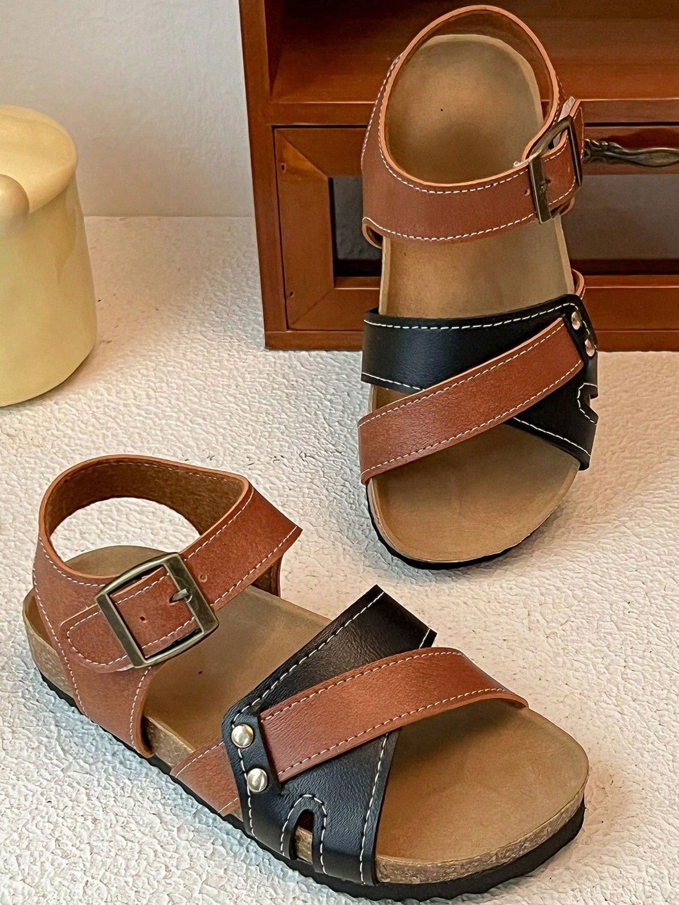 Pair of girls' pink open-toe flat sandals with ankle straps, buckle details, and a non-slip black rubber outsole.