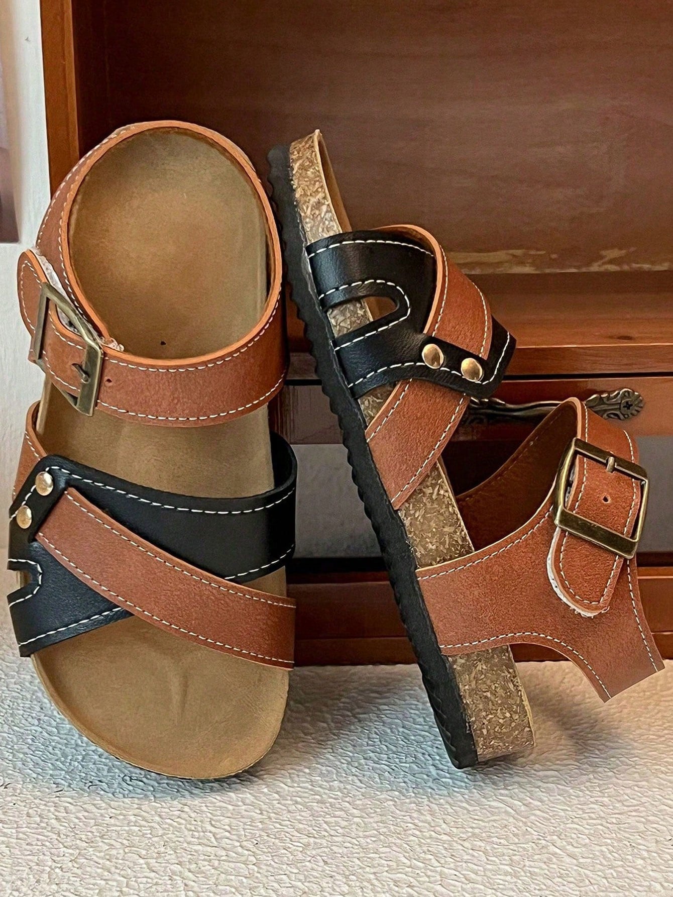 Pair of girls' pink open-toe flat sandals with ankle straps, buckle details, and a non-slip black rubber outsole.