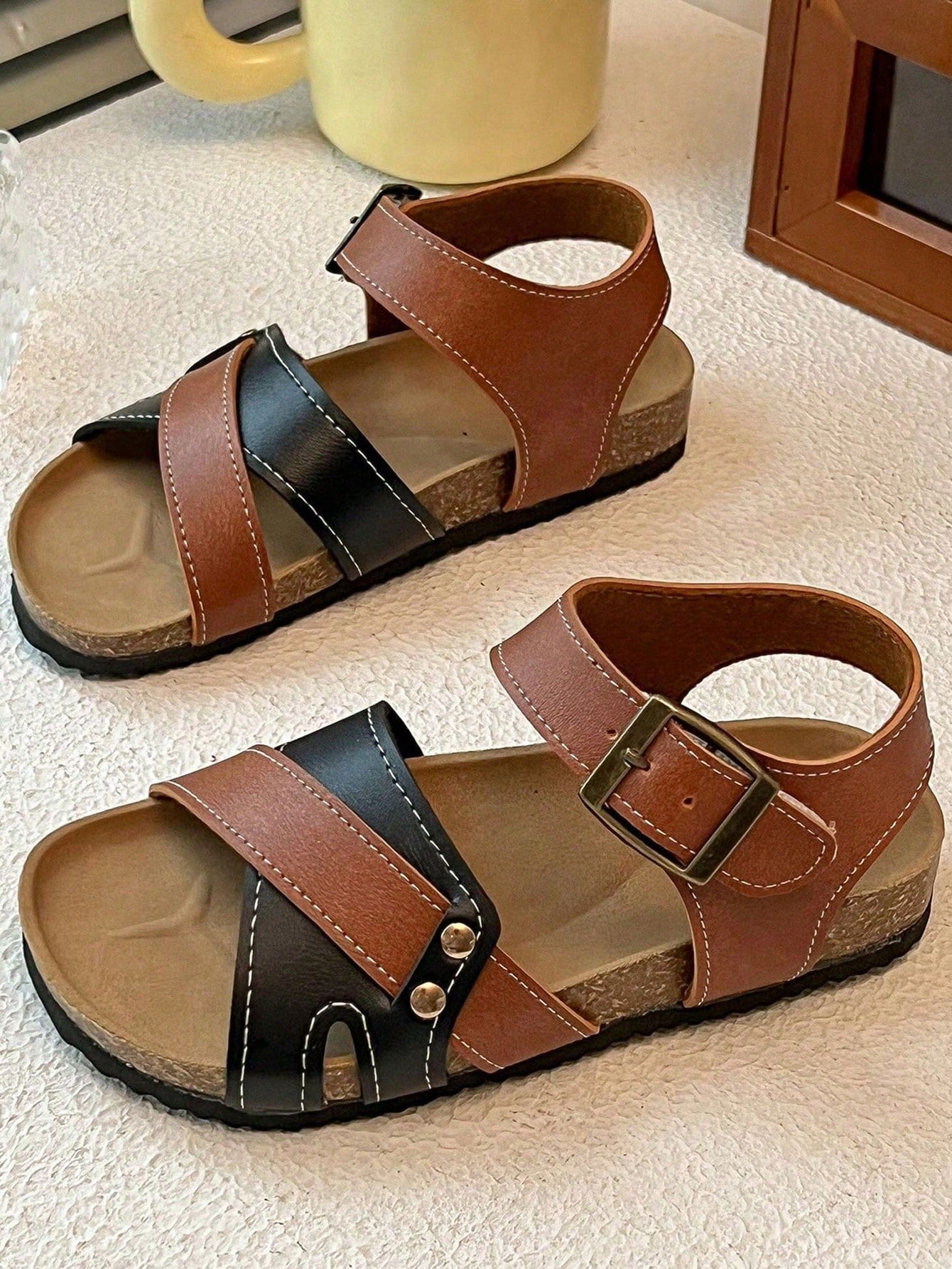 Pair of girls' pink open-toe flat sandals with ankle straps, buckle details, and a non-slip black rubber outsole.