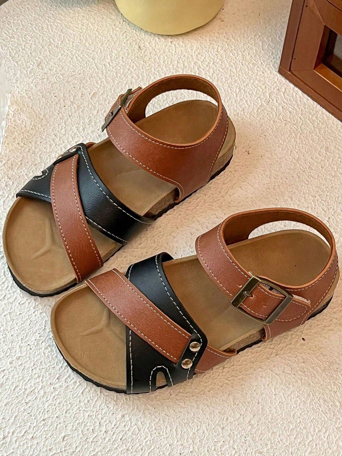 Pair of girls' pink open-toe flat sandals with ankle straps, buckle details, and a non-slip black rubber outsole.