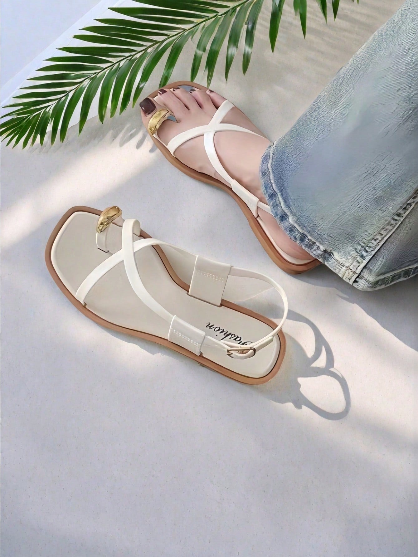 Women's white flat slide sandals featuring criss cross straps, shell detail, and buckle accents