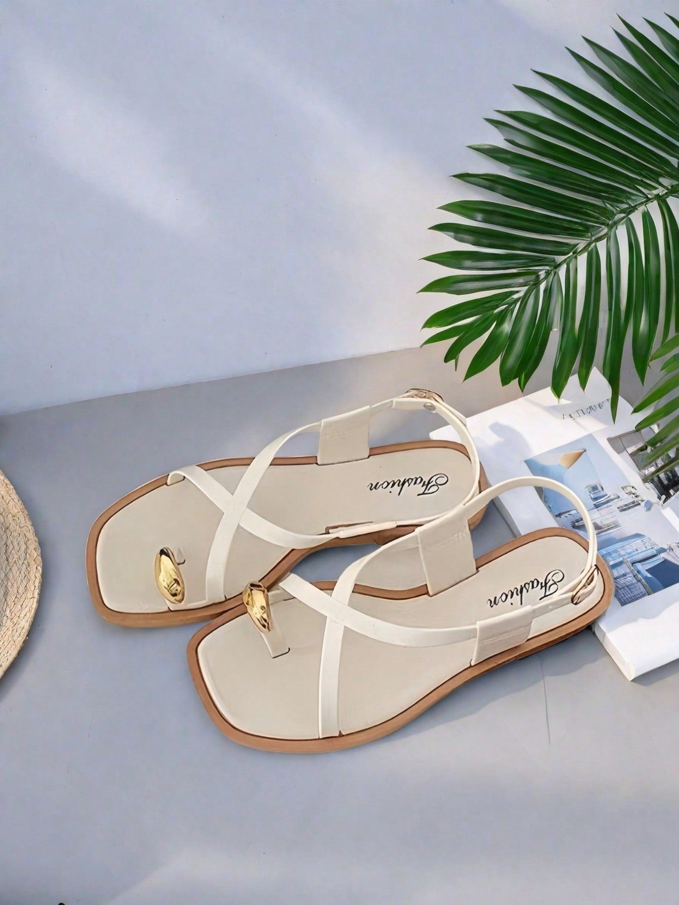 Women's white flat slide sandals featuring criss cross straps, shell detail, and buckle accents