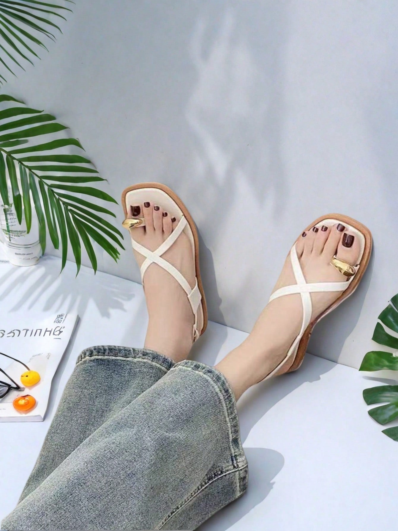 Women's white flat slide sandals featuring criss cross straps, shell detail, and buckle accents