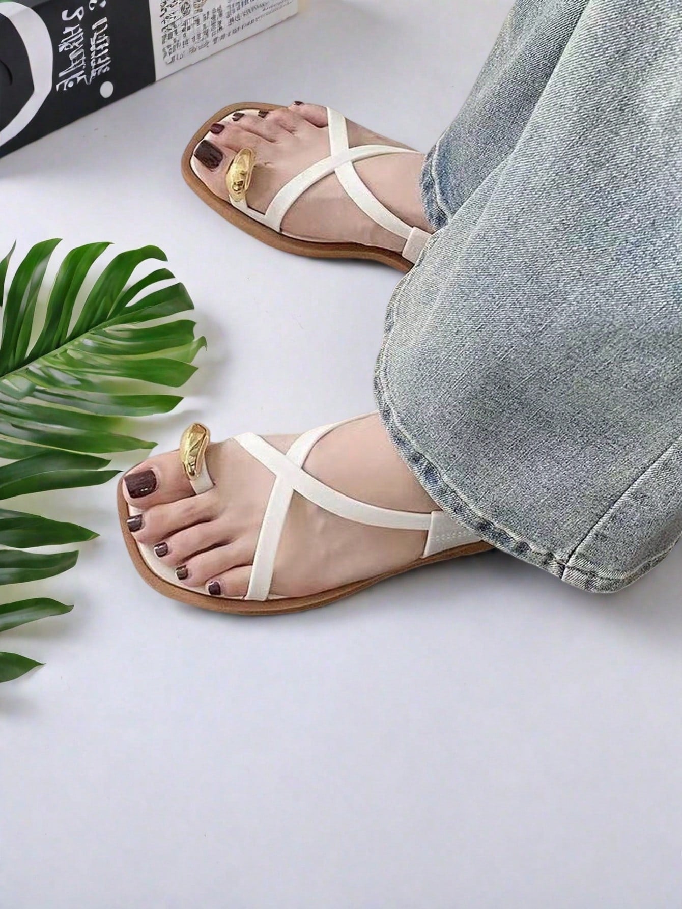 Women's white flat slide sandals featuring criss cross straps, shell detail, and buckle accents
