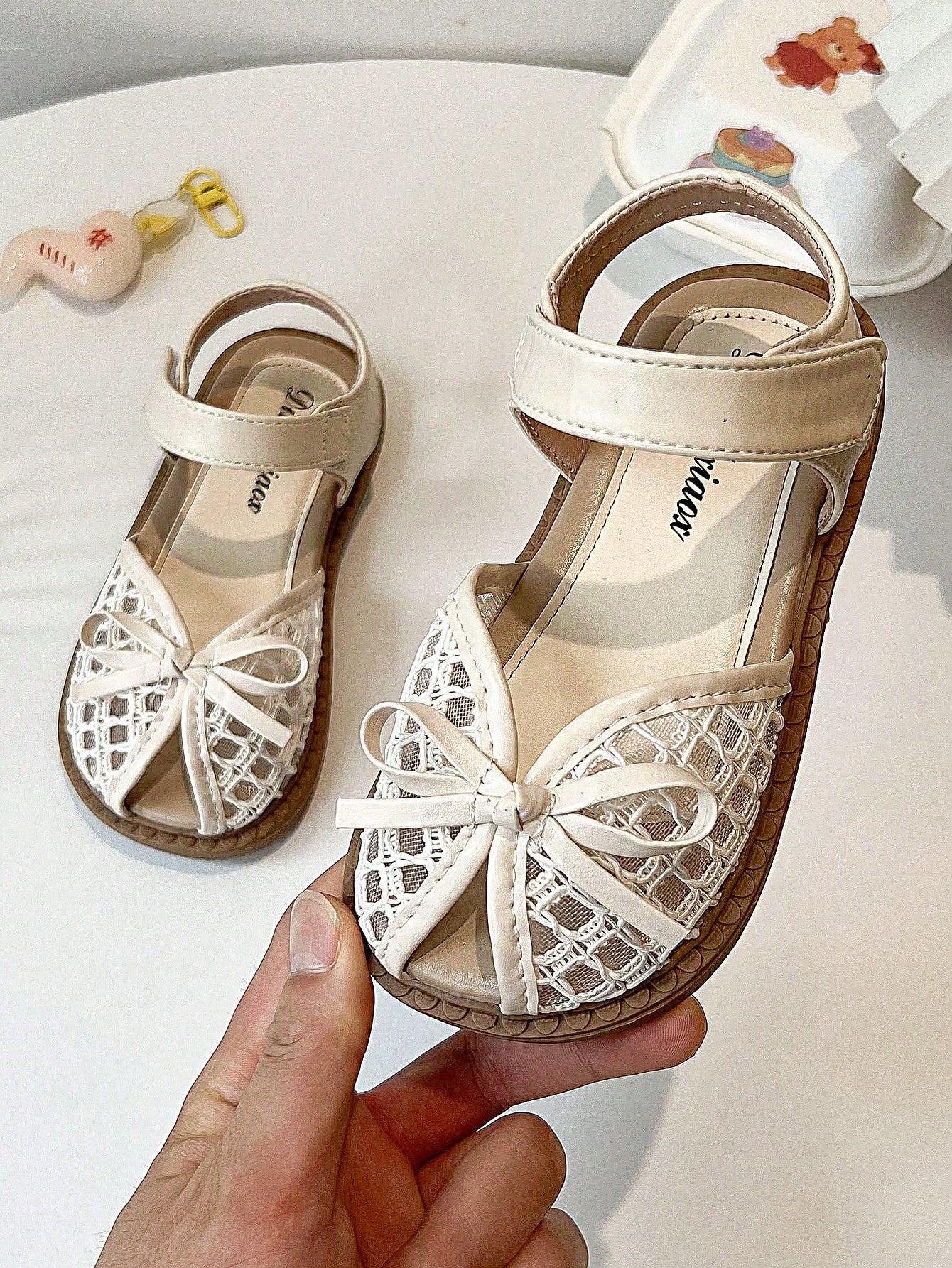 Pair of girls' pink open-toe flat sandals with ankle straps, buckle details, and a non-slip black rubber outsole.