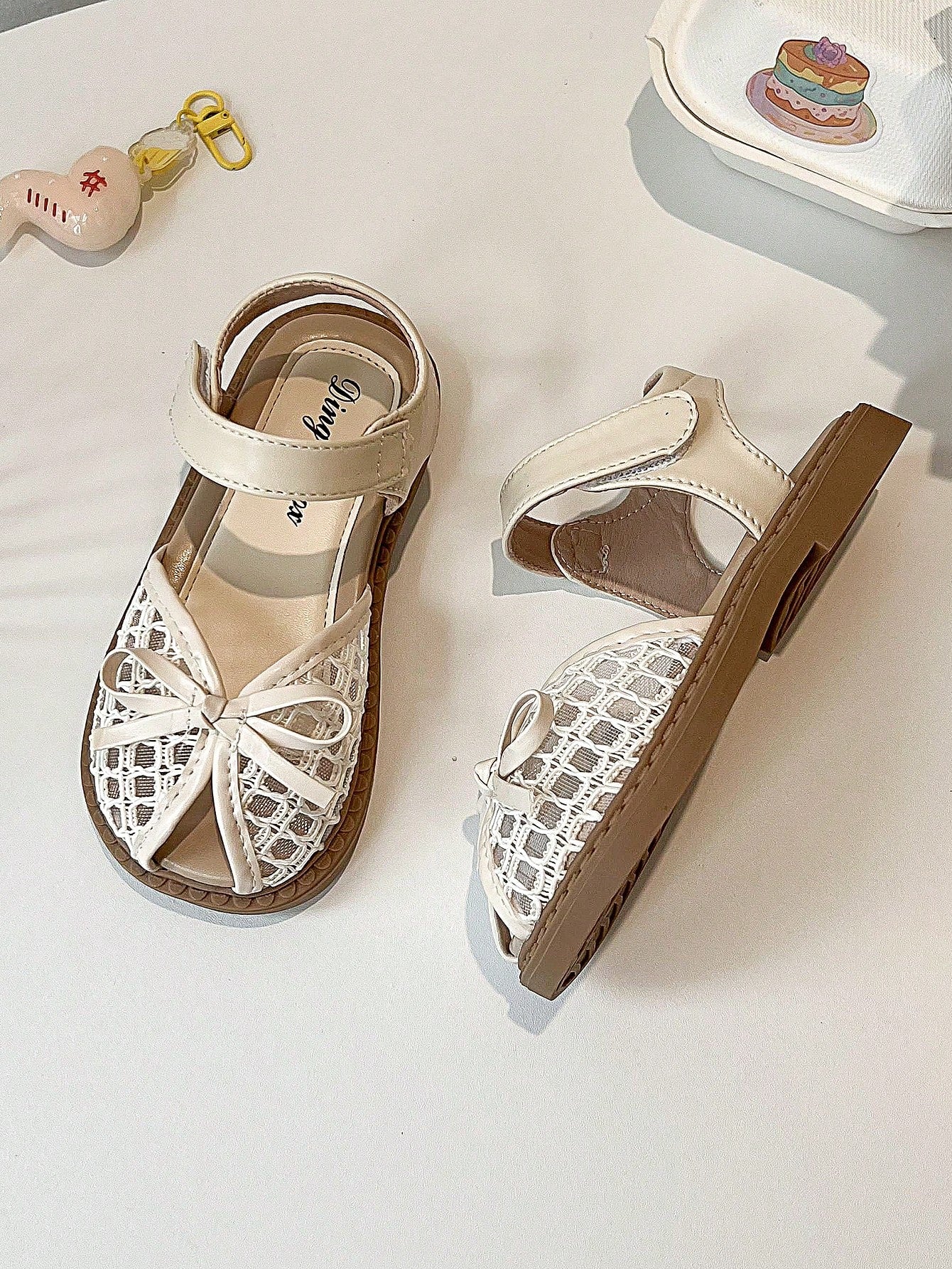 Pair of girls' pink open-toe flat sandals with ankle straps, buckle details, and a non-slip black rubber outsole.