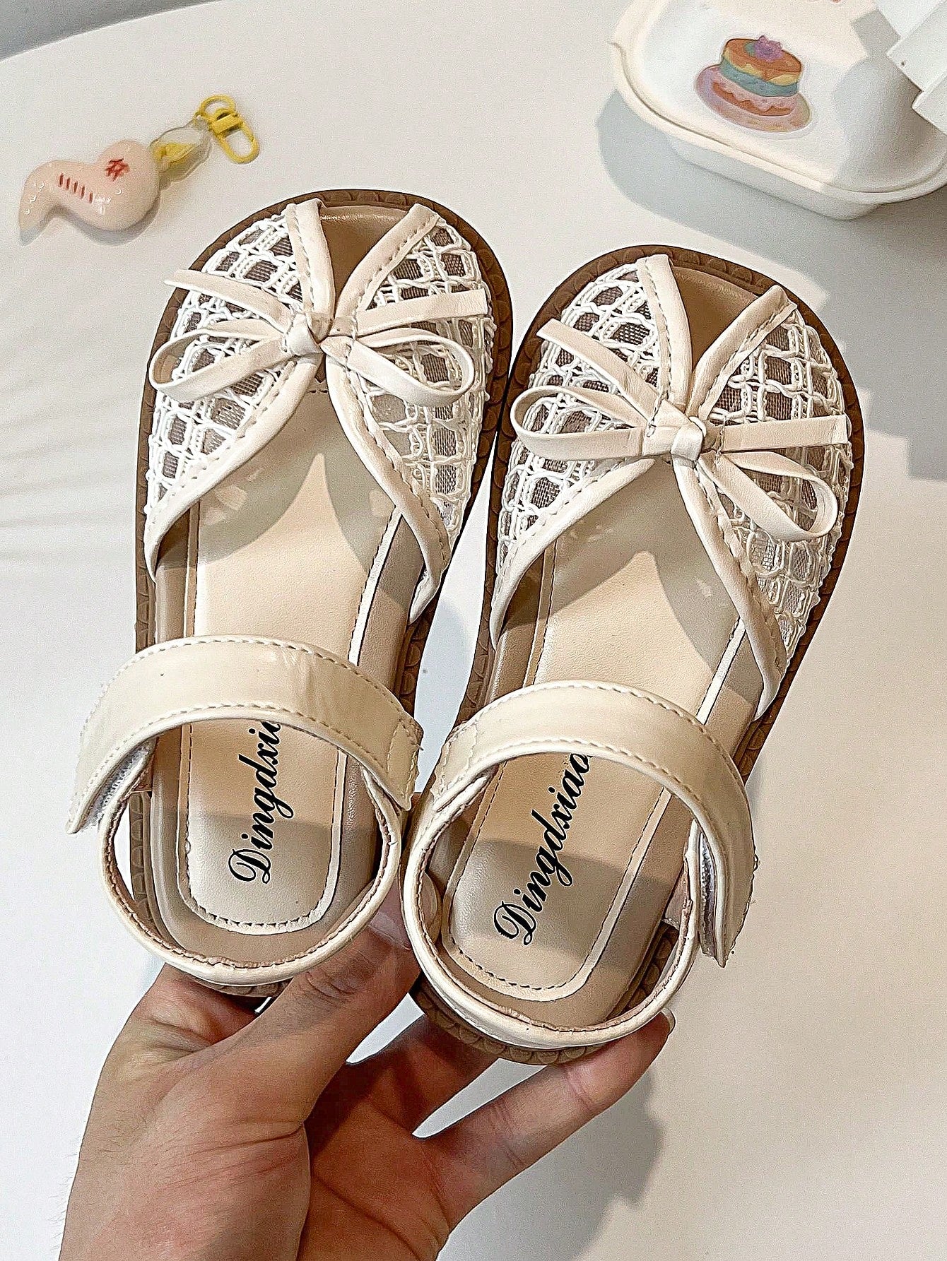 Pair of girls' pink open-toe flat sandals with ankle straps, buckle details, and a non-slip black rubber outsole.