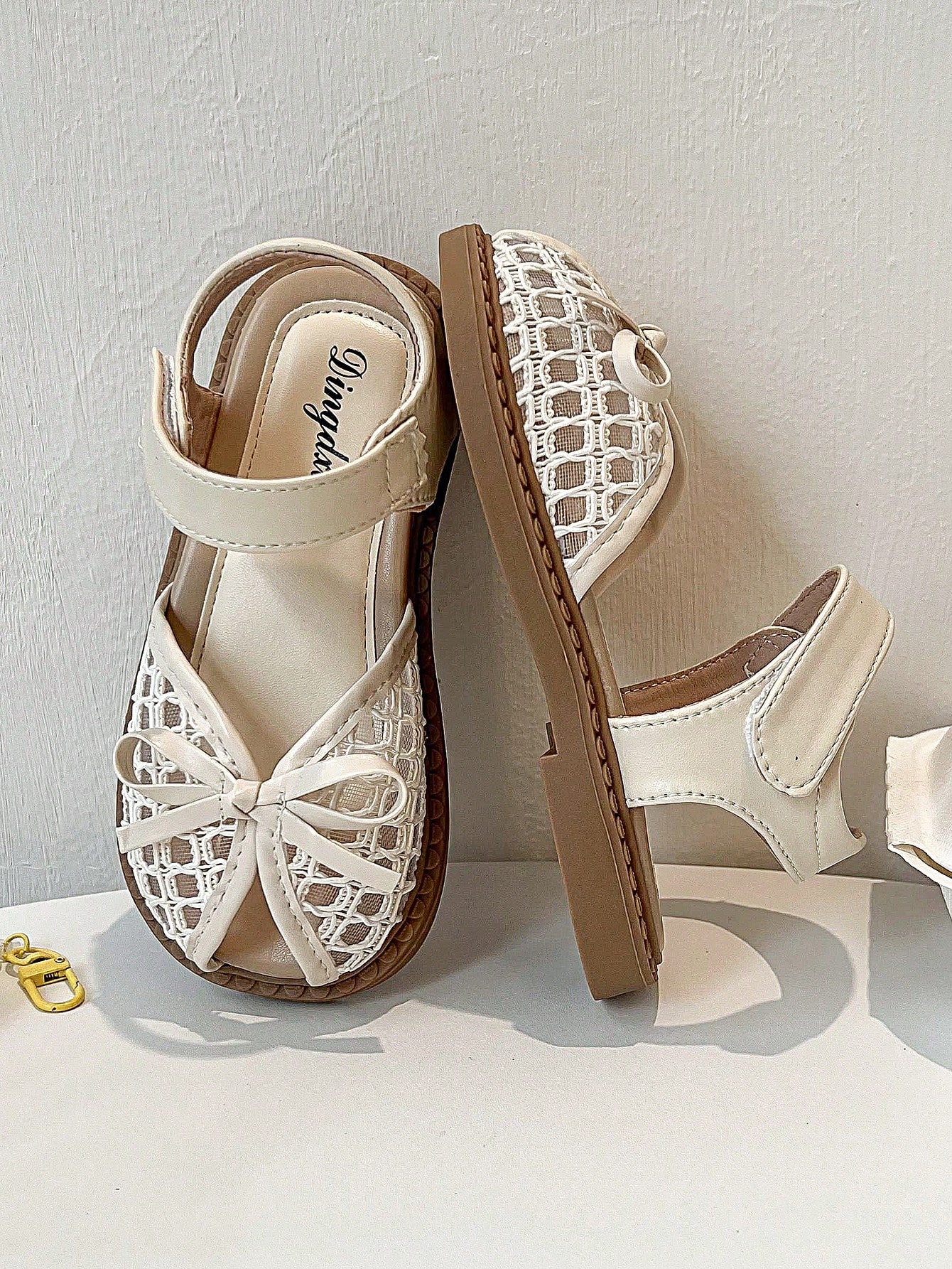 Pair of girls' pink open-toe flat sandals with ankle straps, buckle details, and a non-slip black rubber outsole.