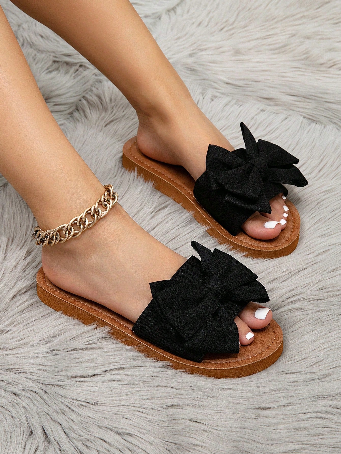 Women's flat slide sandals with ruched fabric, bow accent, and fringe detail, suitable for outdoor vacation wear.