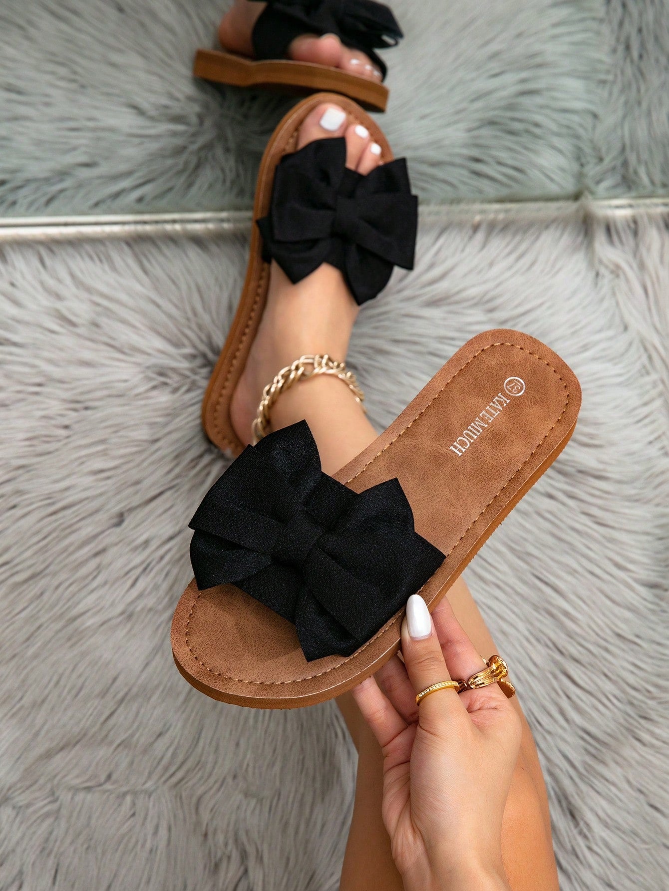 Women's flat slide sandals with ruched fabric, bow accent, and fringe detail, suitable for outdoor vacation wear.