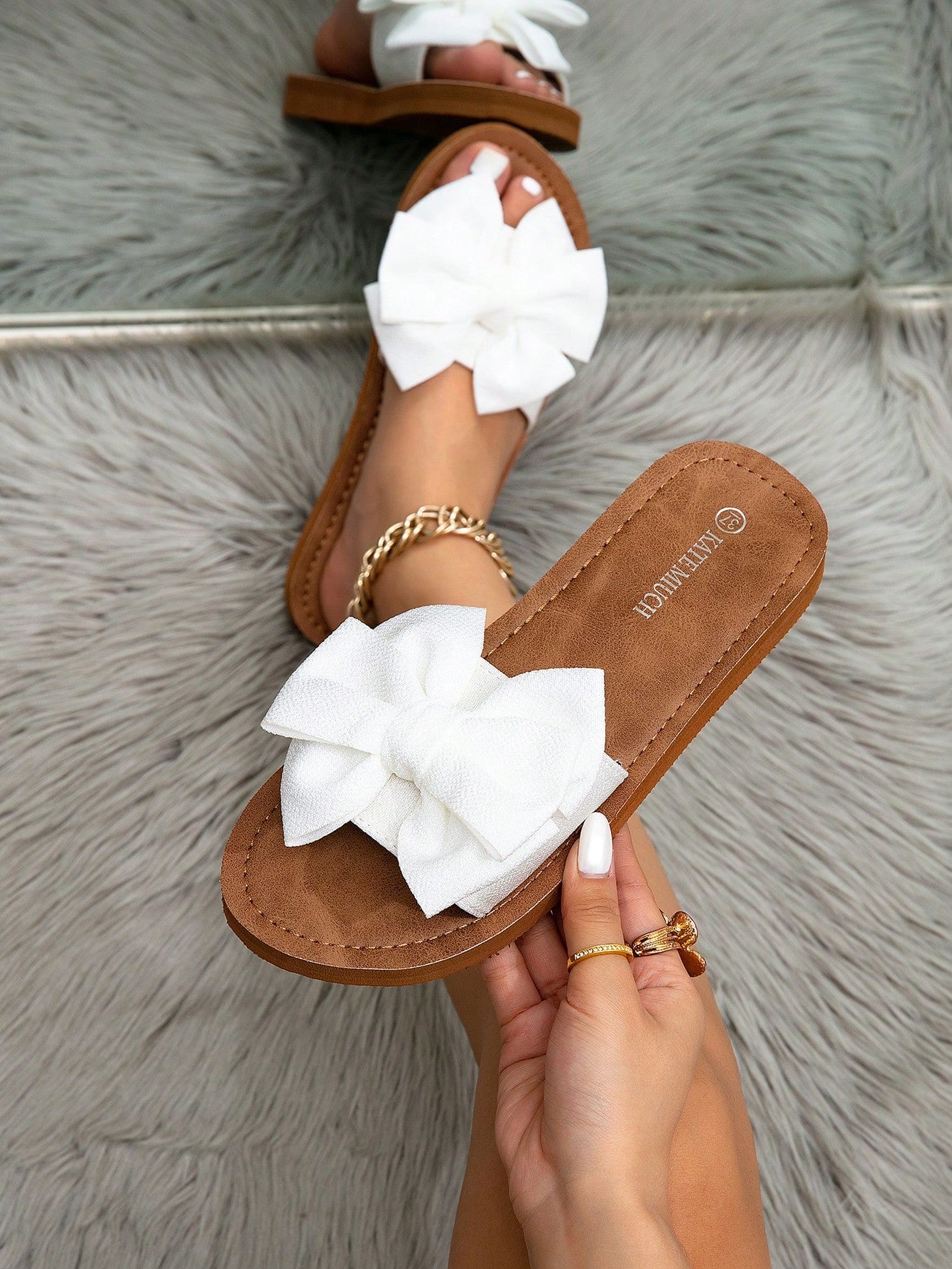Women's flat slide sandals with ruched fabric, bow accent, and fringe detail, suitable for outdoor vacation wear.