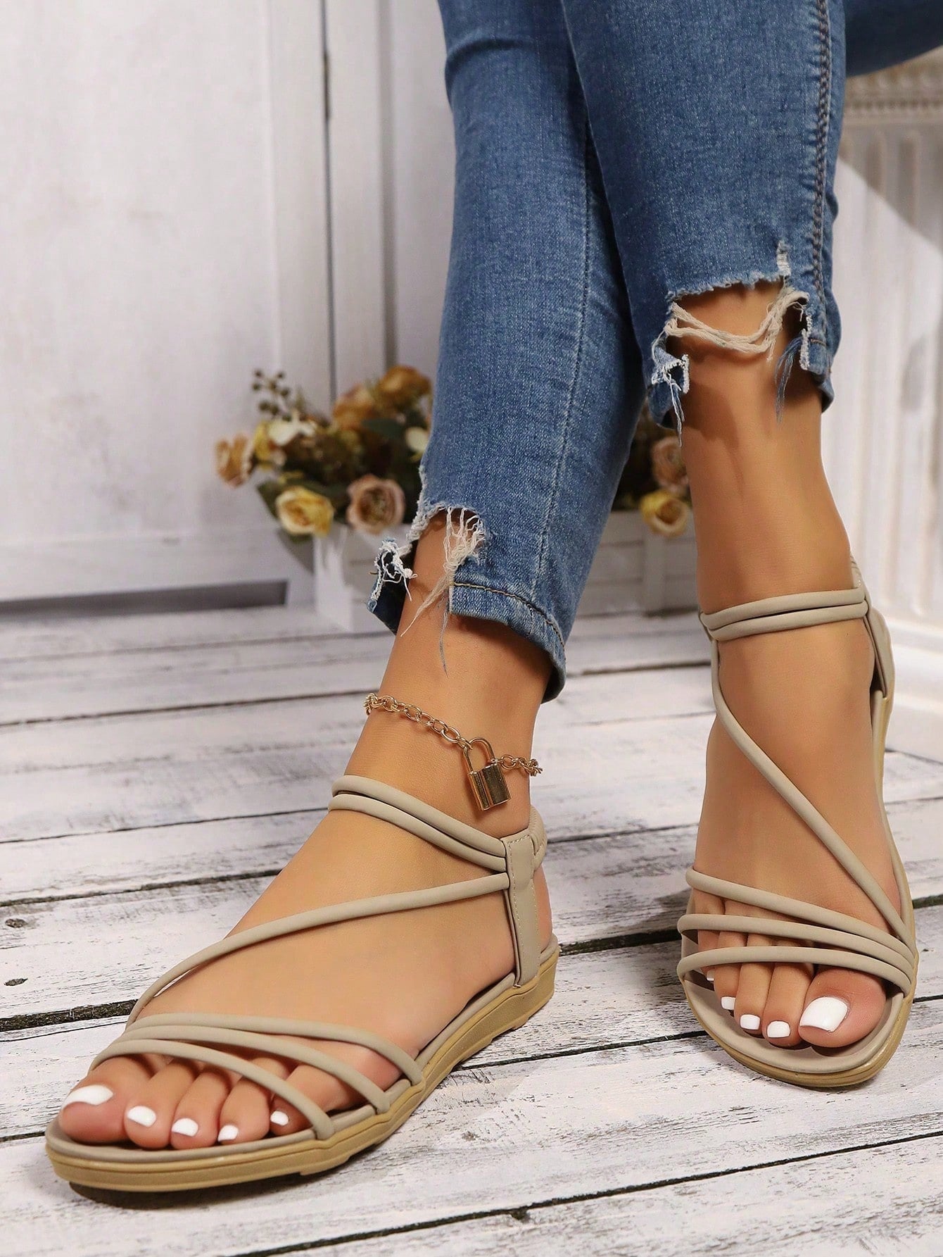 Pair of women's elegant criss cross flat sandals with open toe design, ankle strap, and buckle detail in PU leather.