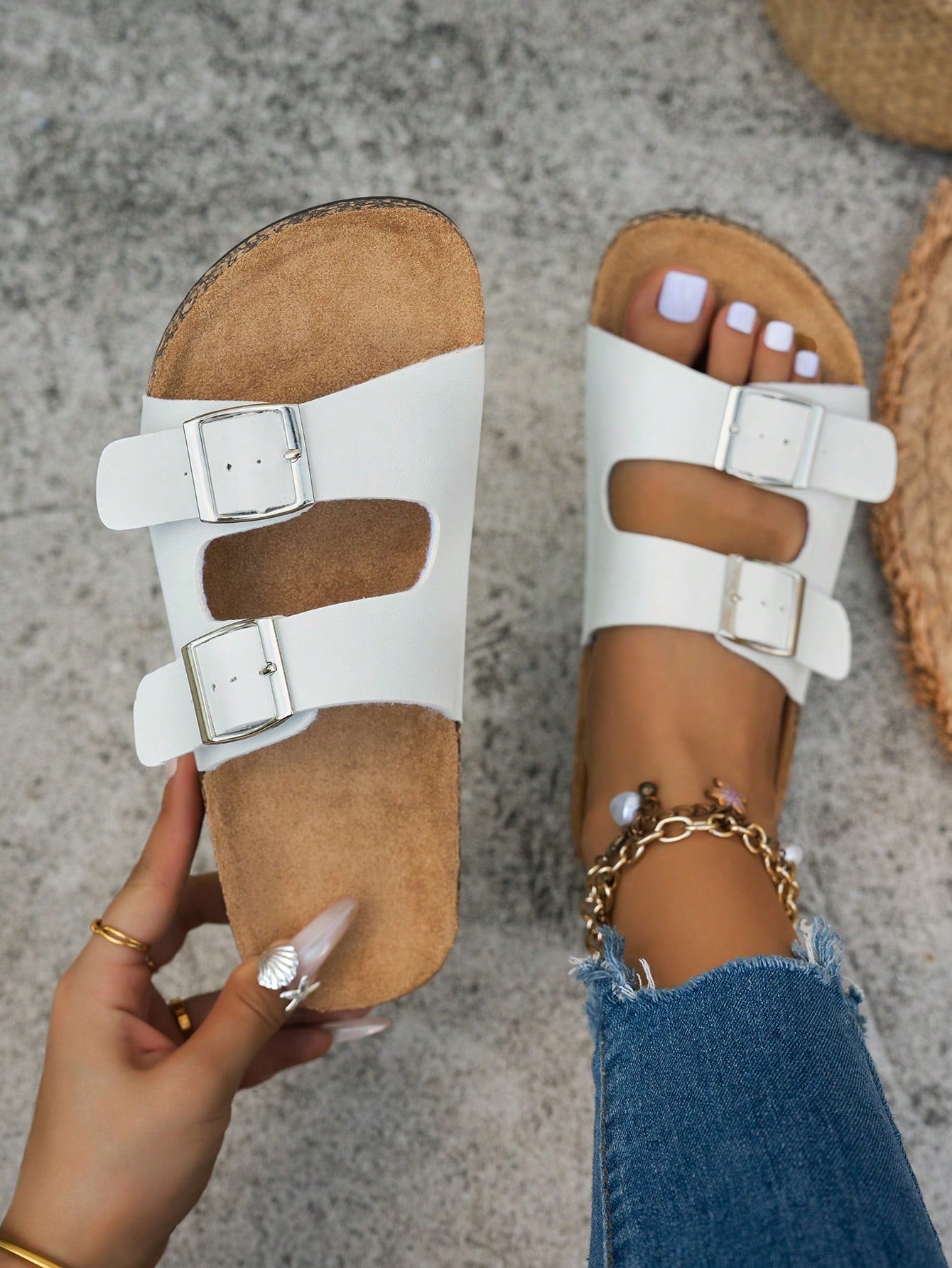 Classic white flat slide sandals with buckle detail and open-toe design.