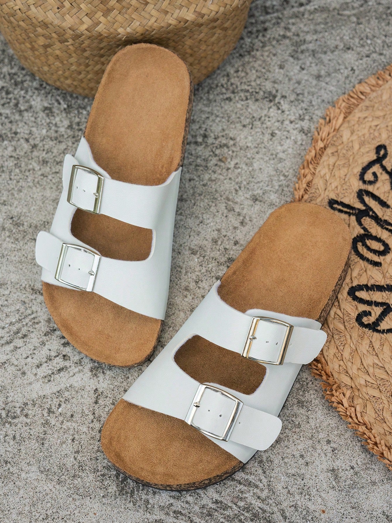 Classic white flat slide sandals with buckle detail and open-toe design.