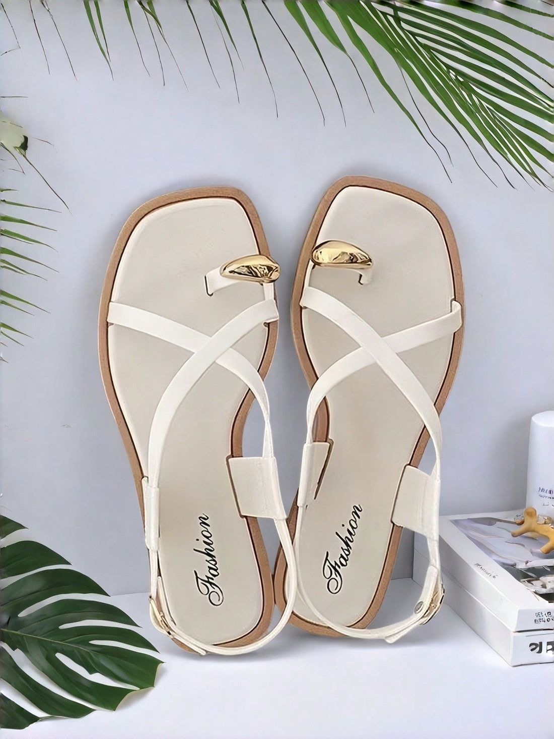 Women's white flat slide sandals featuring criss cross straps, shell detail, and buckle accents
