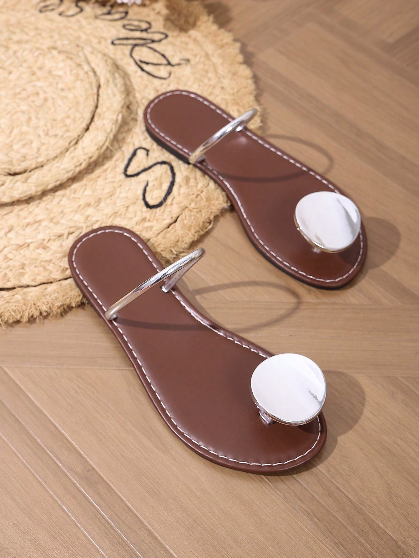 Women’s flat thong sandals with a shiny round buckle, high-gloss finish, semi-circle strap, and toe post design