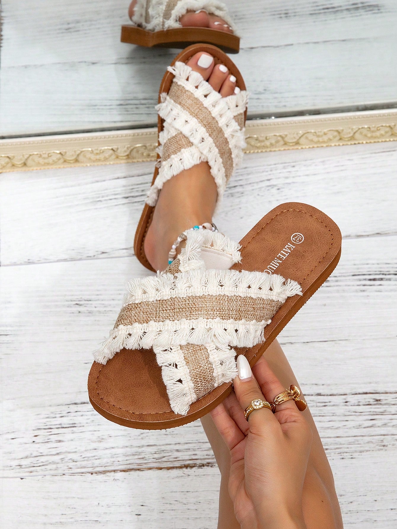 Women's flat slide sandals with ruched fabric, bow accent, and fringe detail, suitable for outdoor vacation wear.